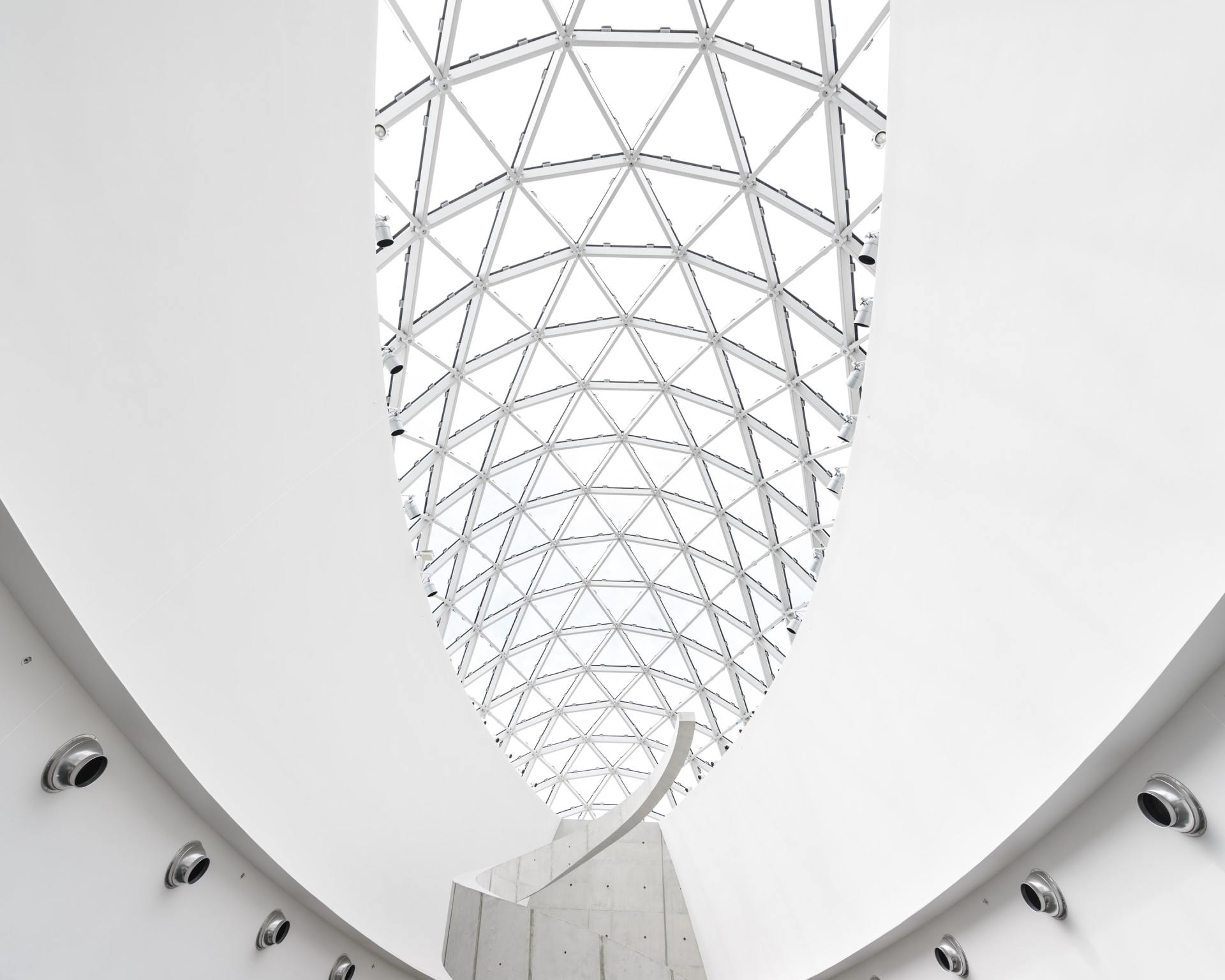 White, arched ceiling with geometric glass paneling; modern architecture.