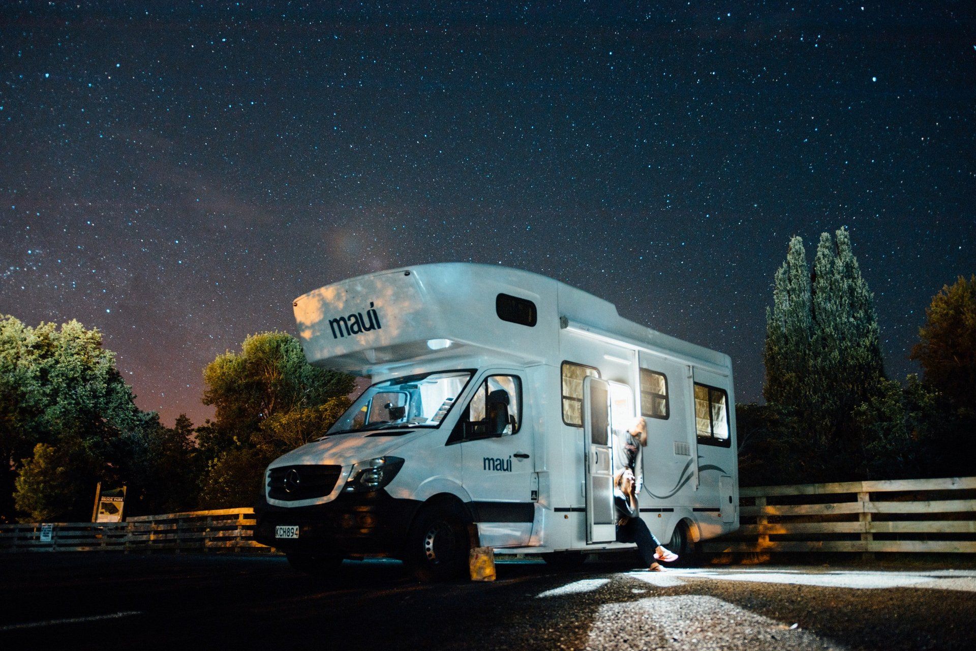 Couple sitting in the doorway of the RV gazing at the Stars