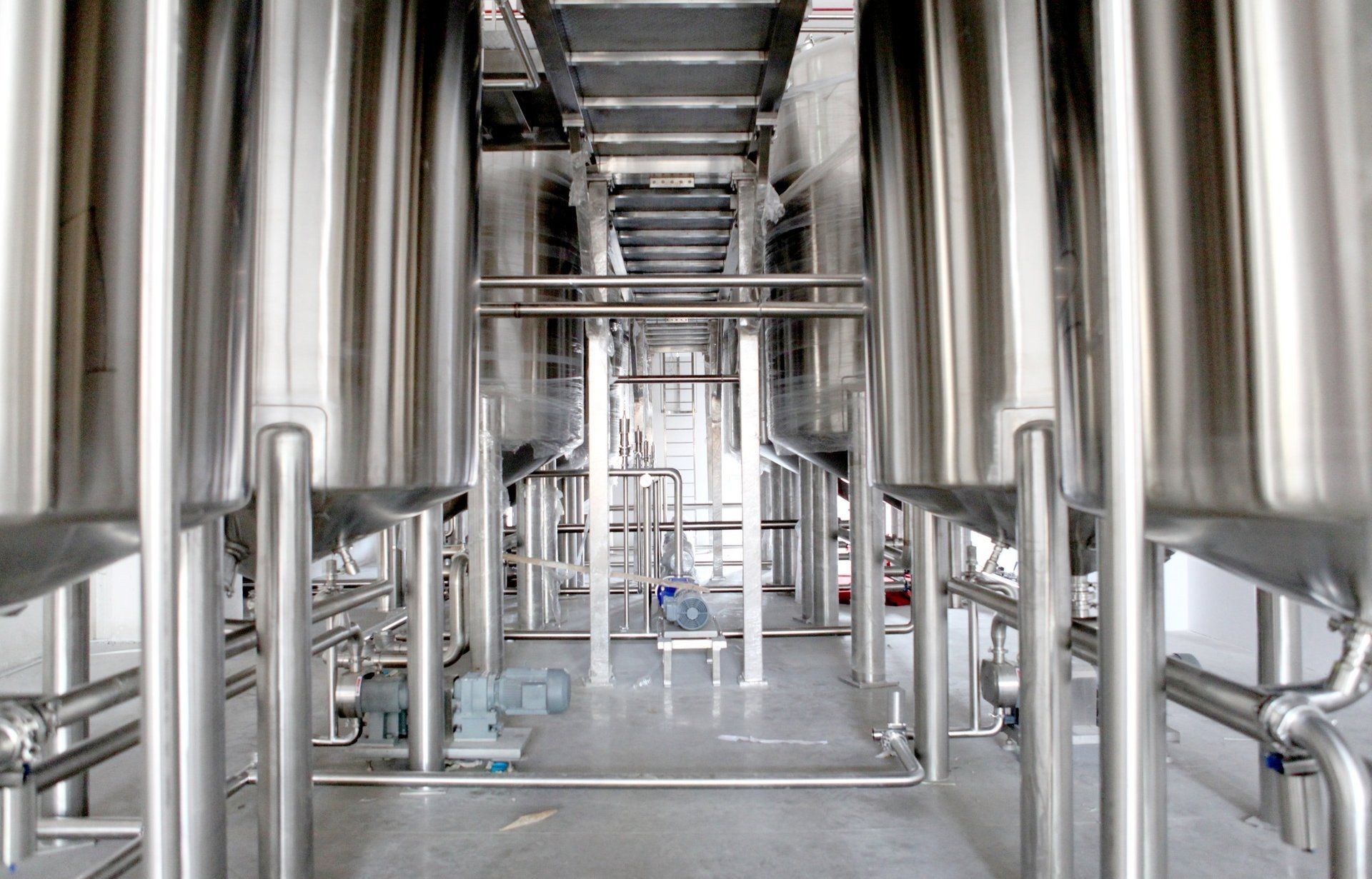 A row of stainless steel tanks in a factory.