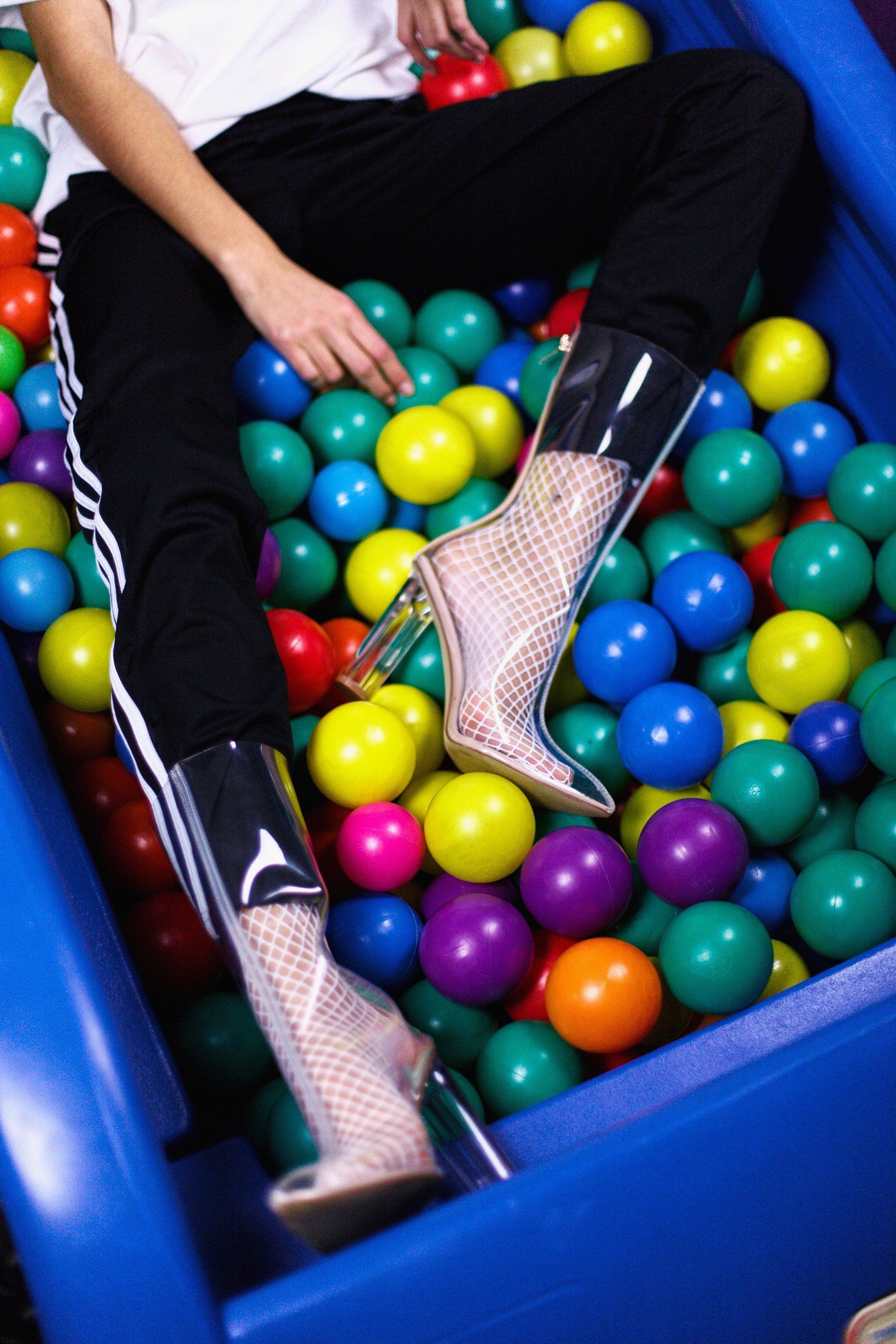 A person is sitting in a pool of colorful plastic balls