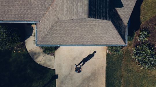An aerial view of a house with a shadow of a person on the driveway
