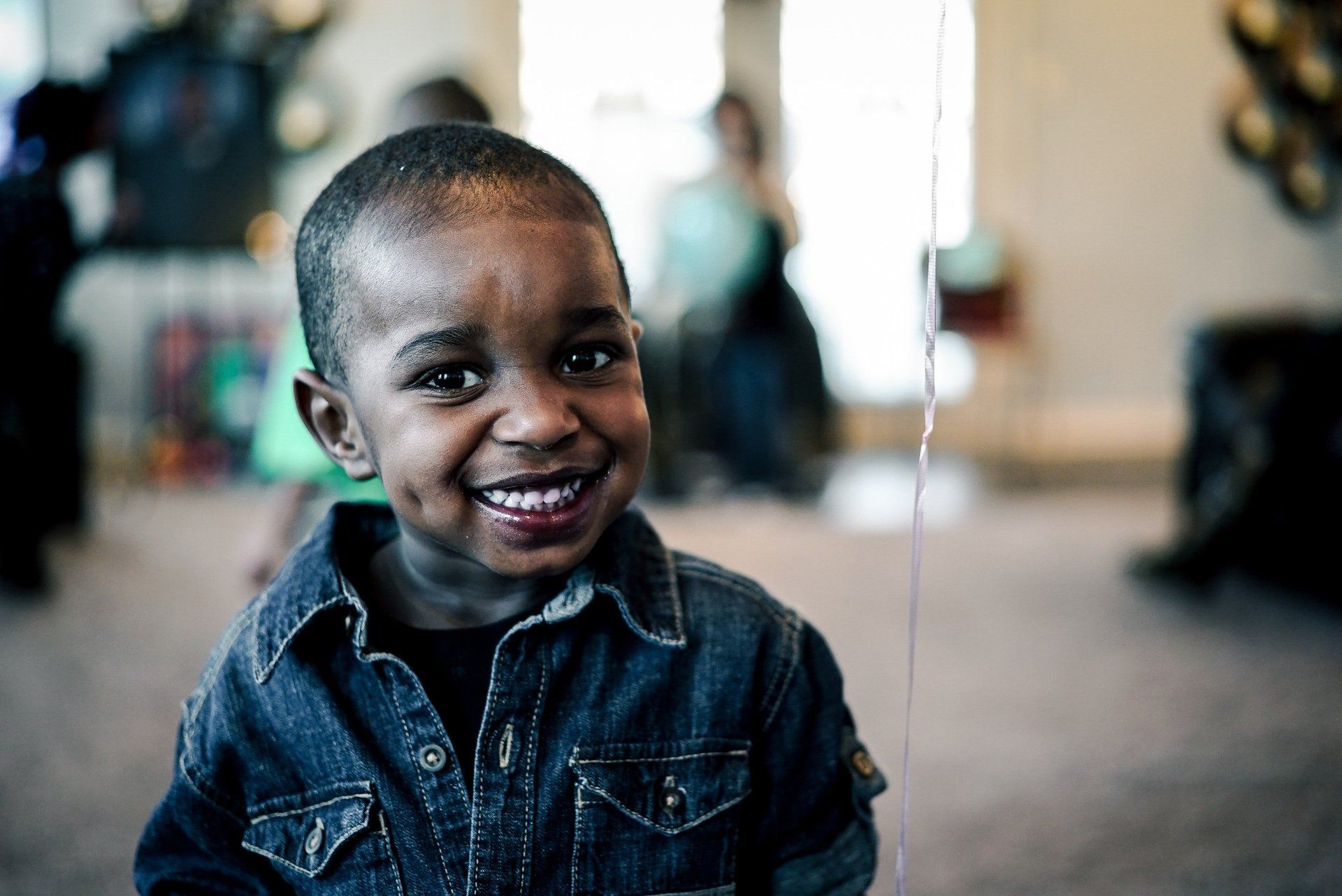 Black boy smiles at camera wearing jean jacket