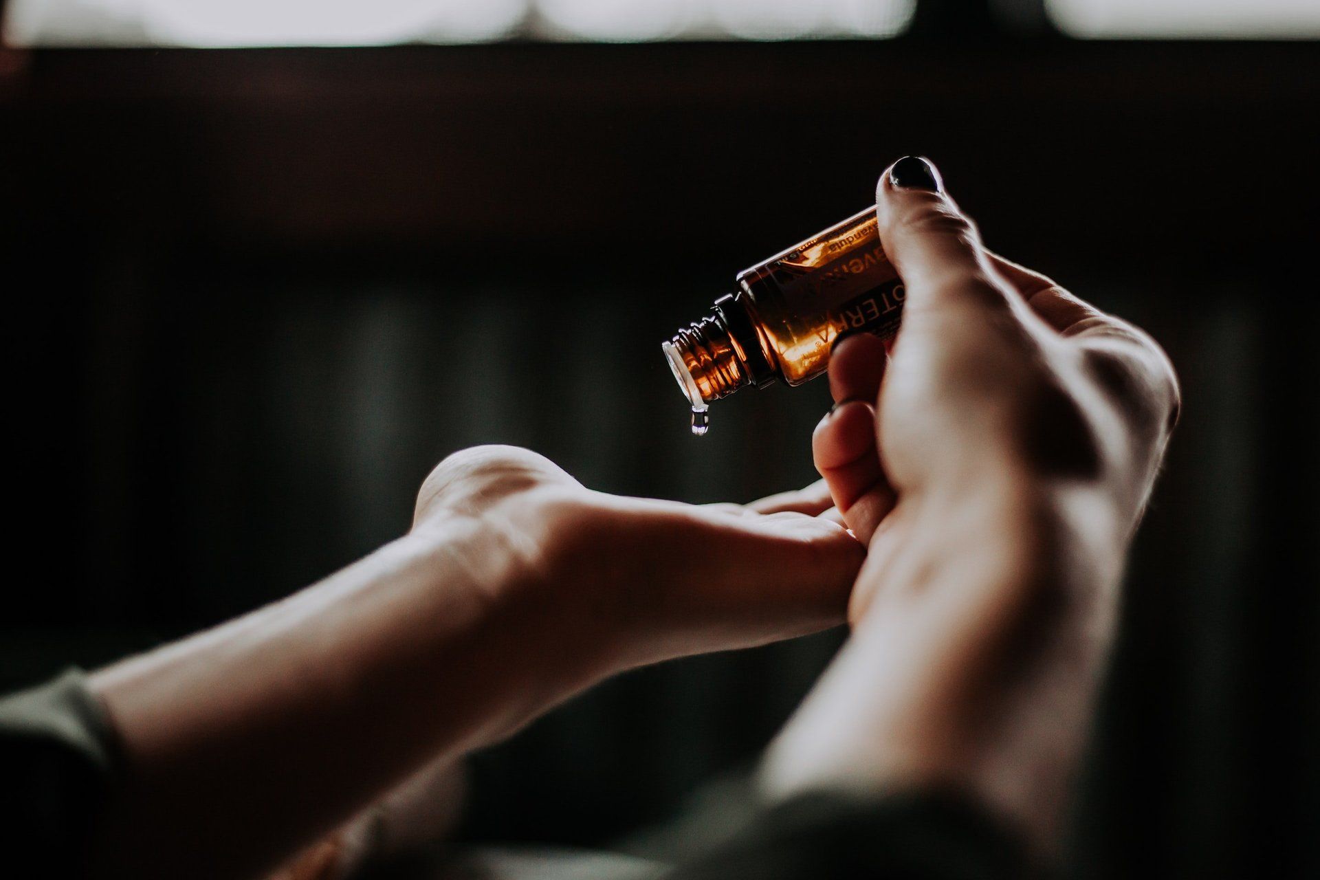 A woman is pouring essential oil into her hand.