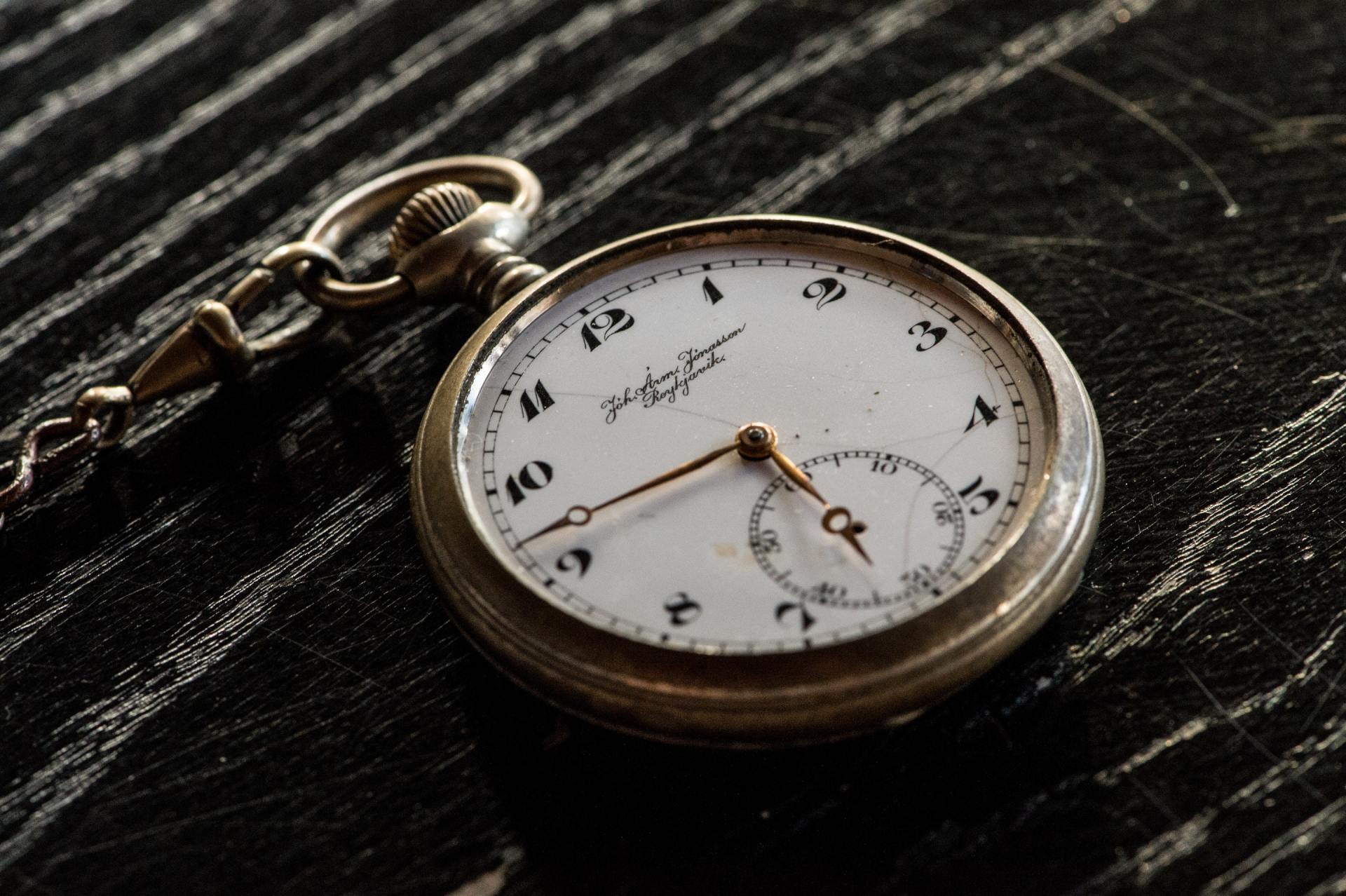 A pocket watch is sitting on a wooden table