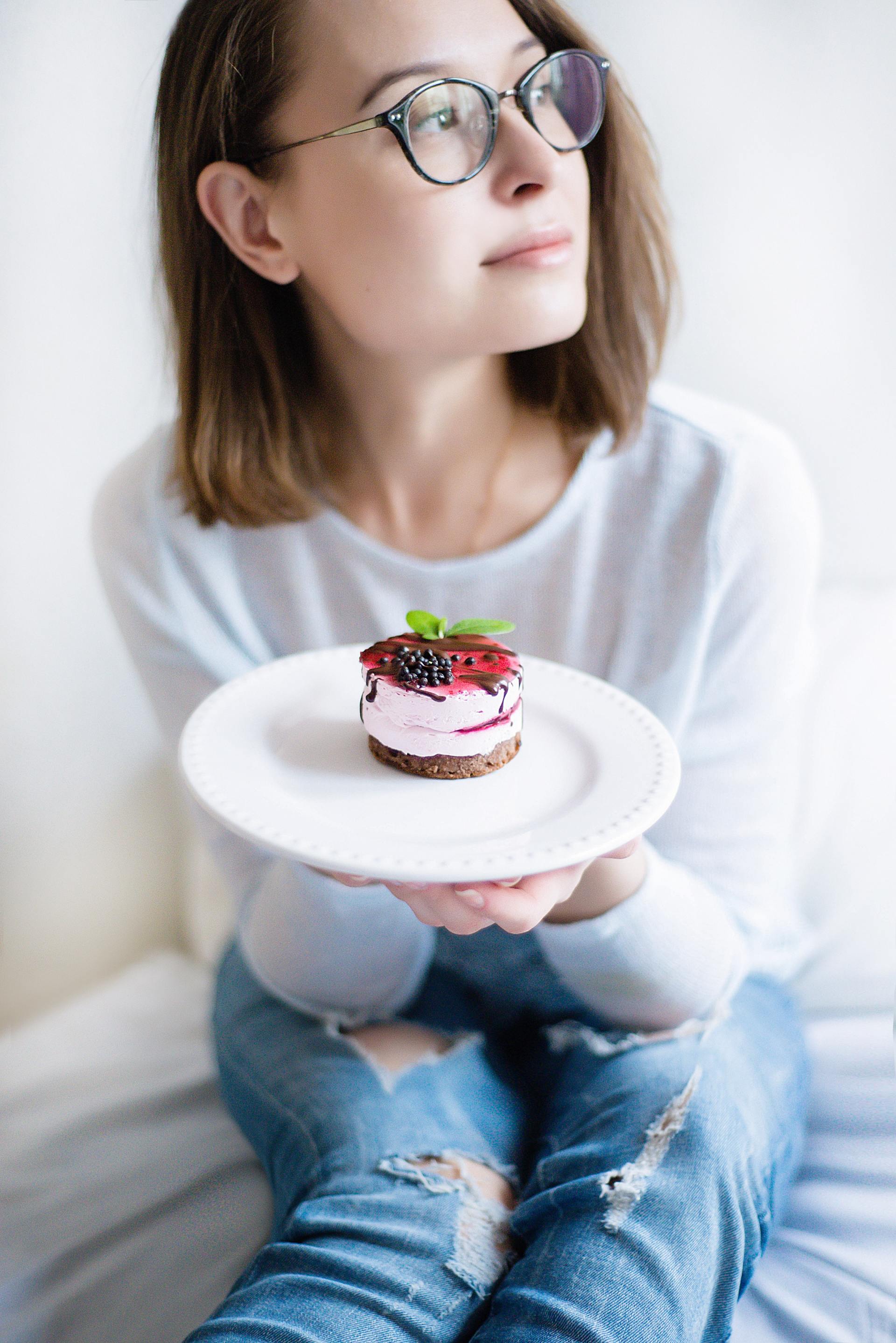 A girl considering to eat a cheesecake.