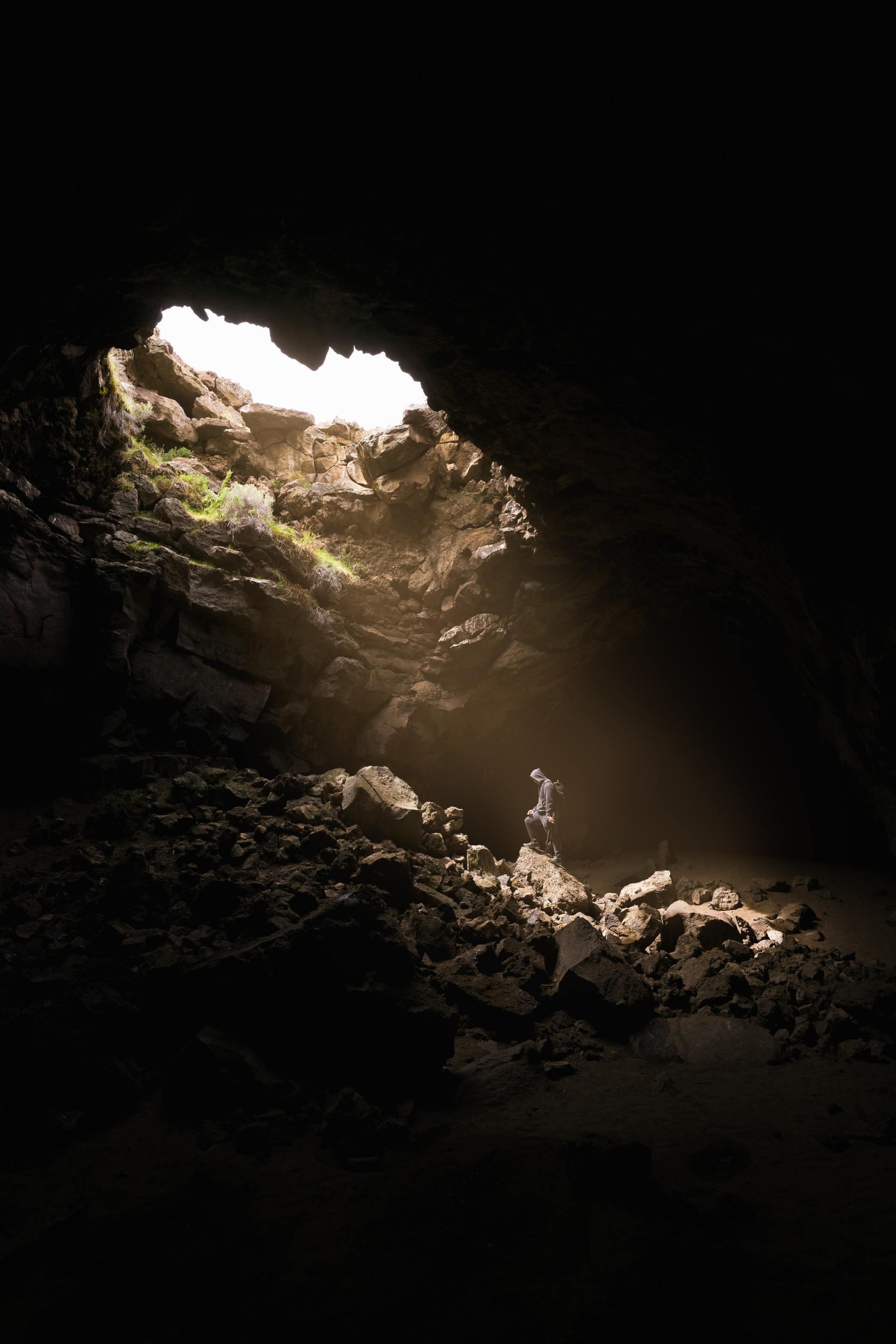 image of a deep cave with person looking up and thinking