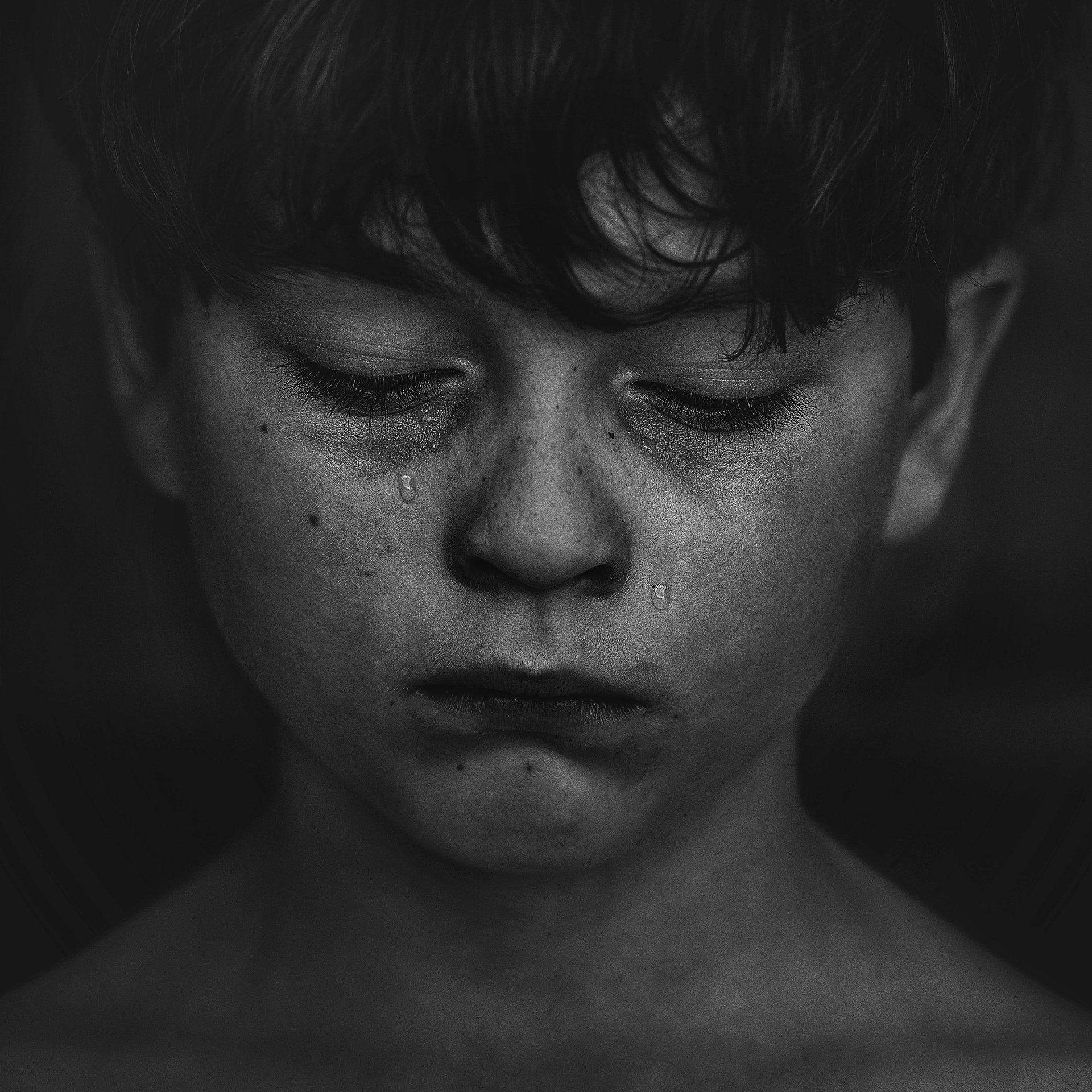 Sad boys' face with tears reminds us of inner pain
