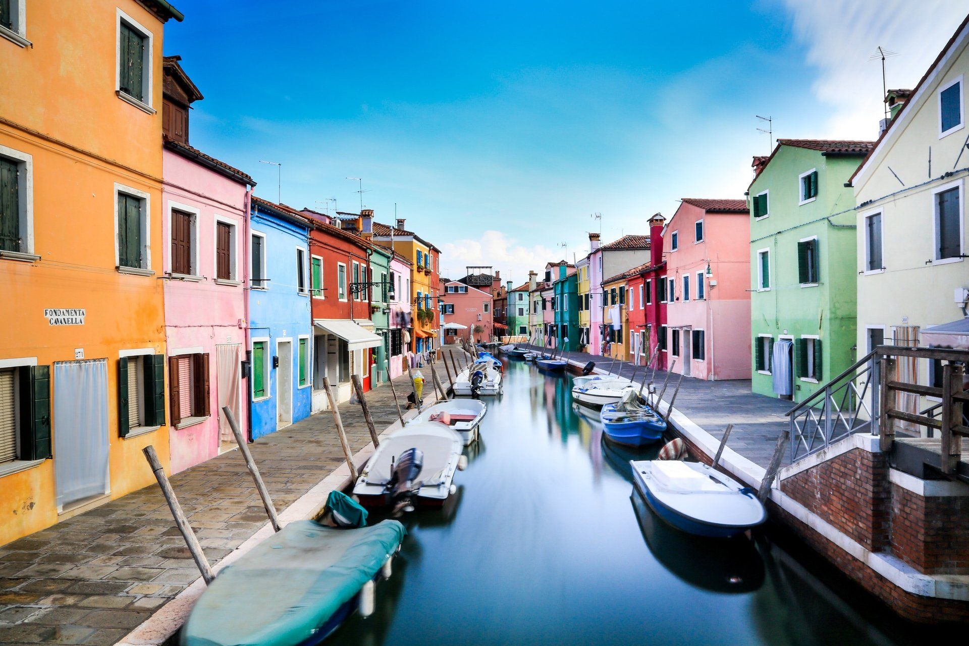A row of colorful buildings along a canal with boats in the water.