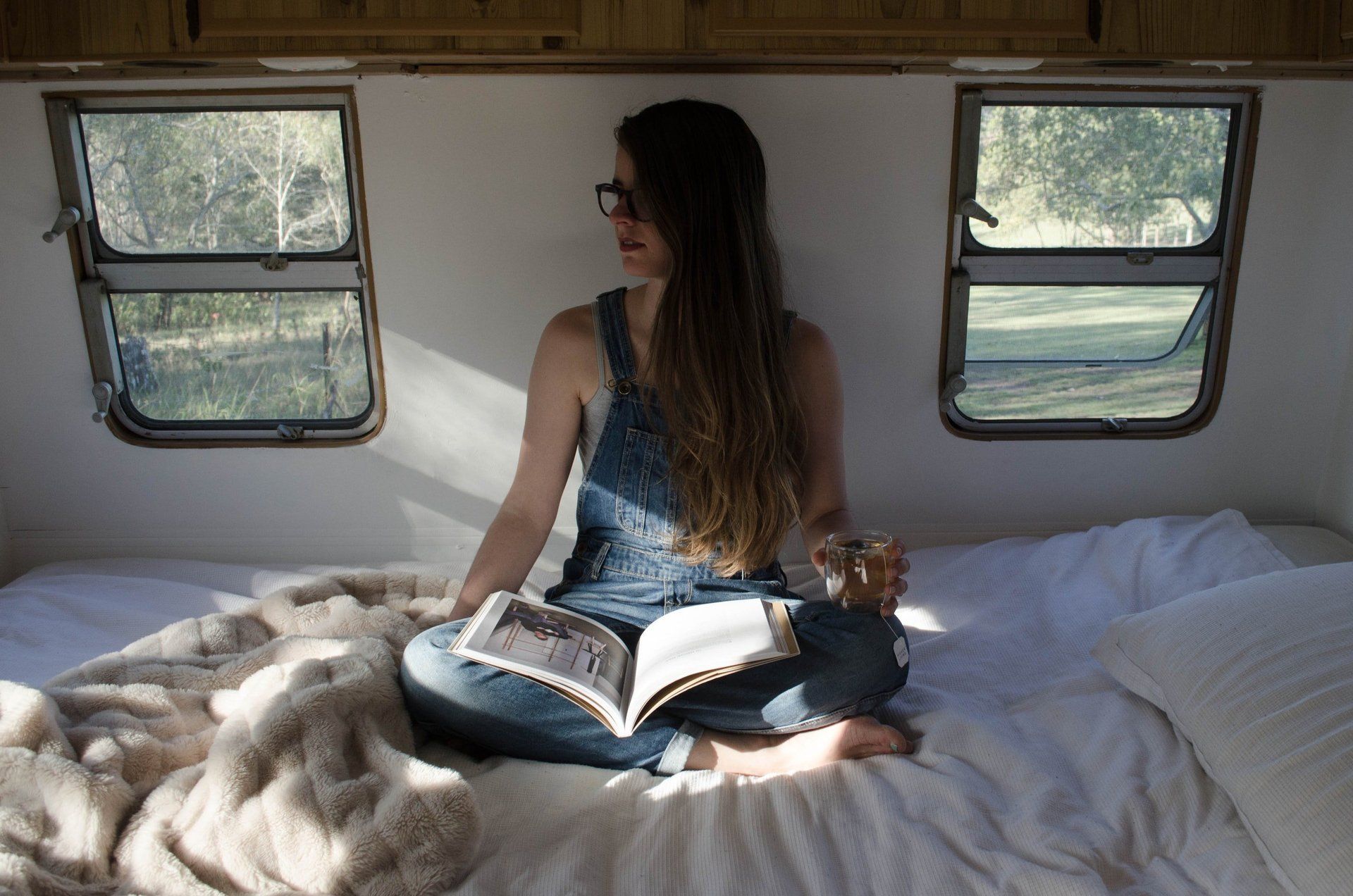 Girl sitting in motorhome with book on her lap