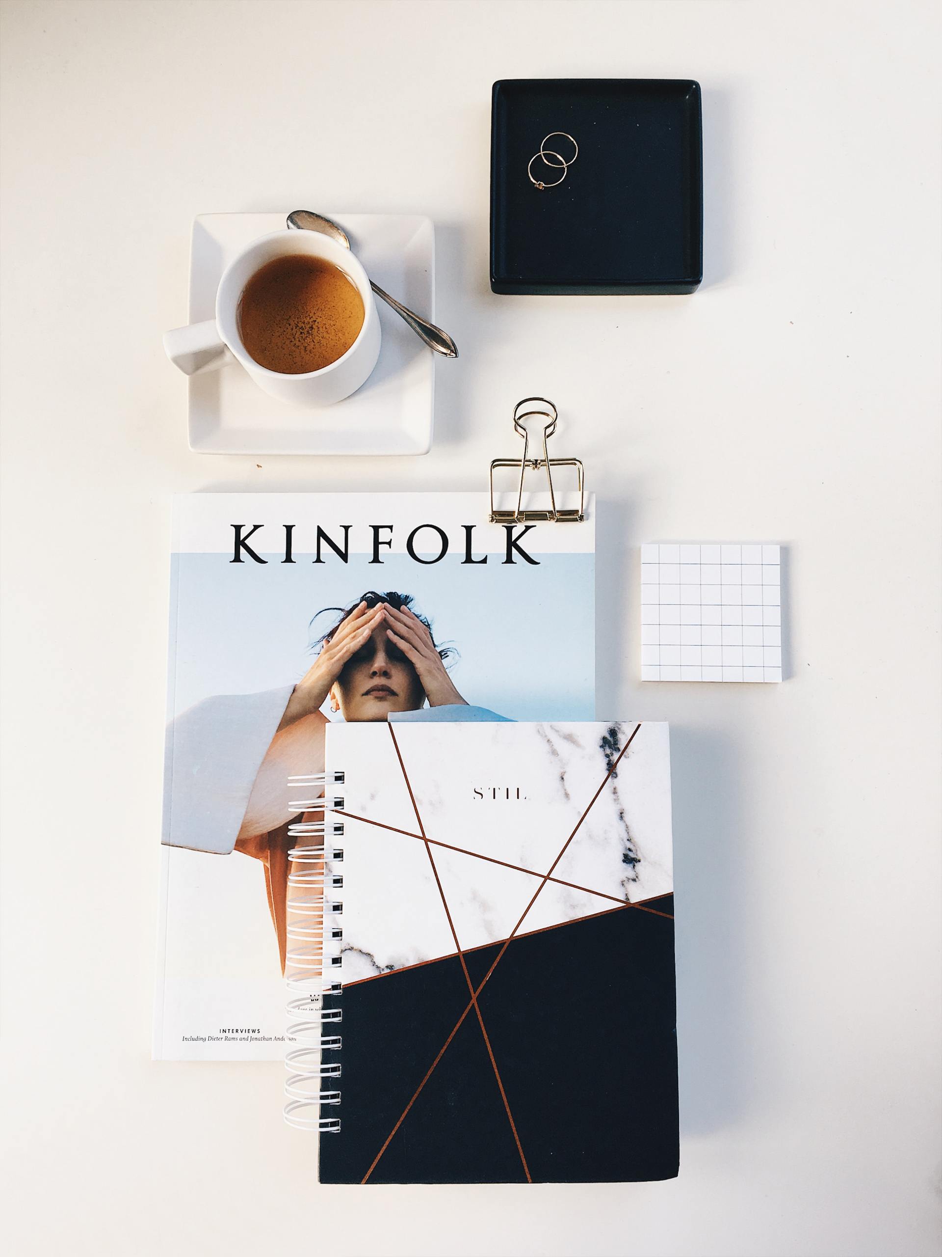 A book titled kinfolk sits on a table next to a cup of coffee