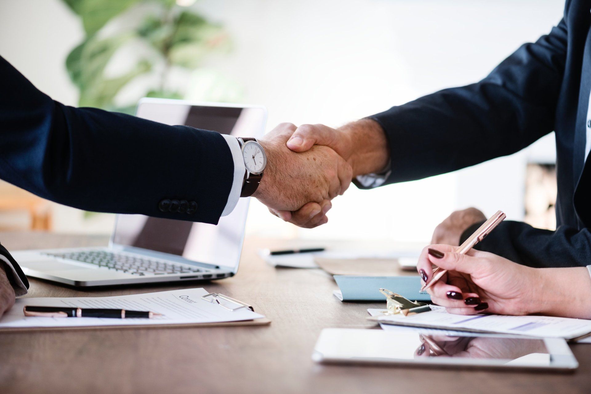 Two arms reaching out to shake hands over a table with notes