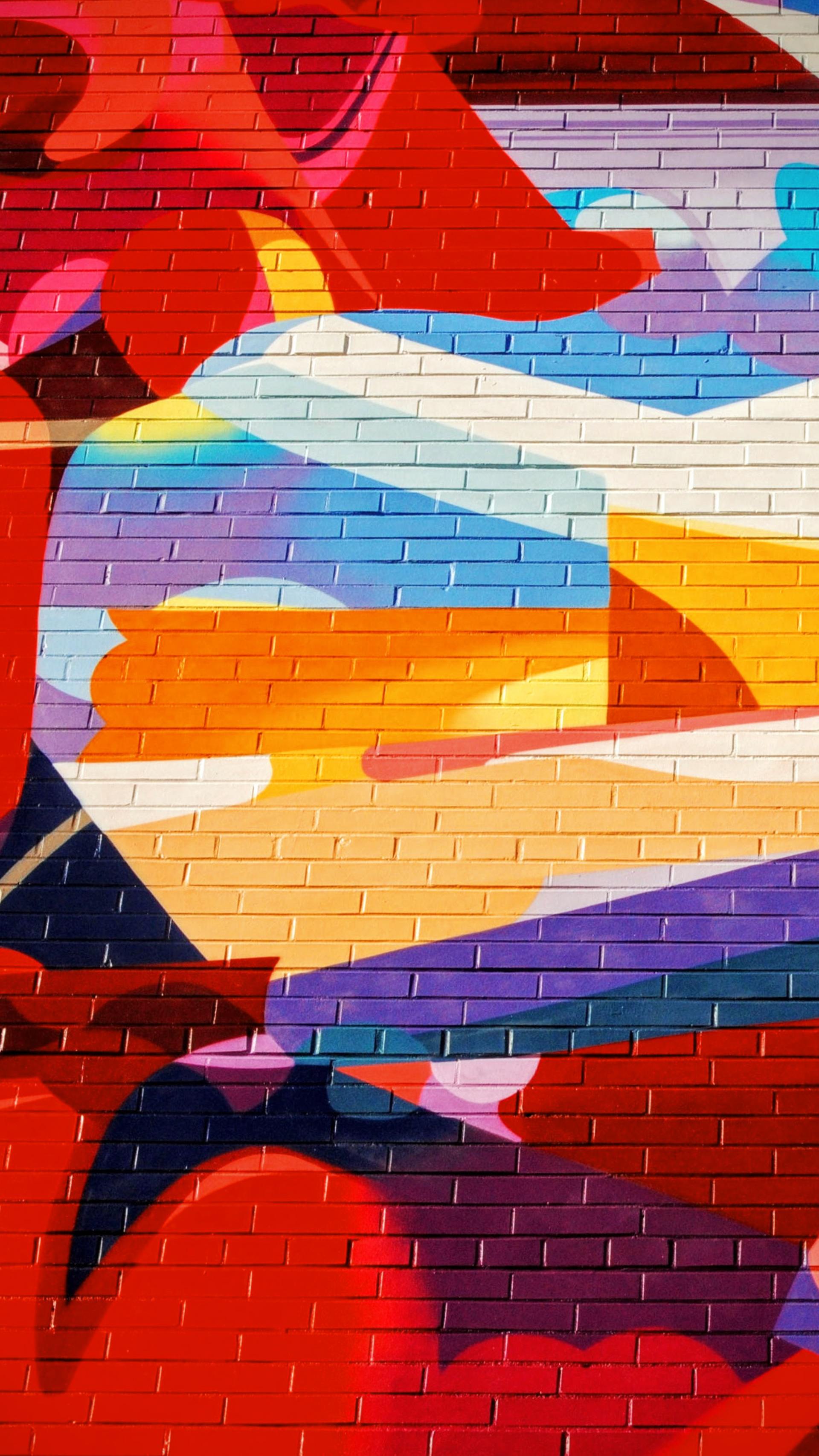 A close up of a colorful painting on a brick wall.