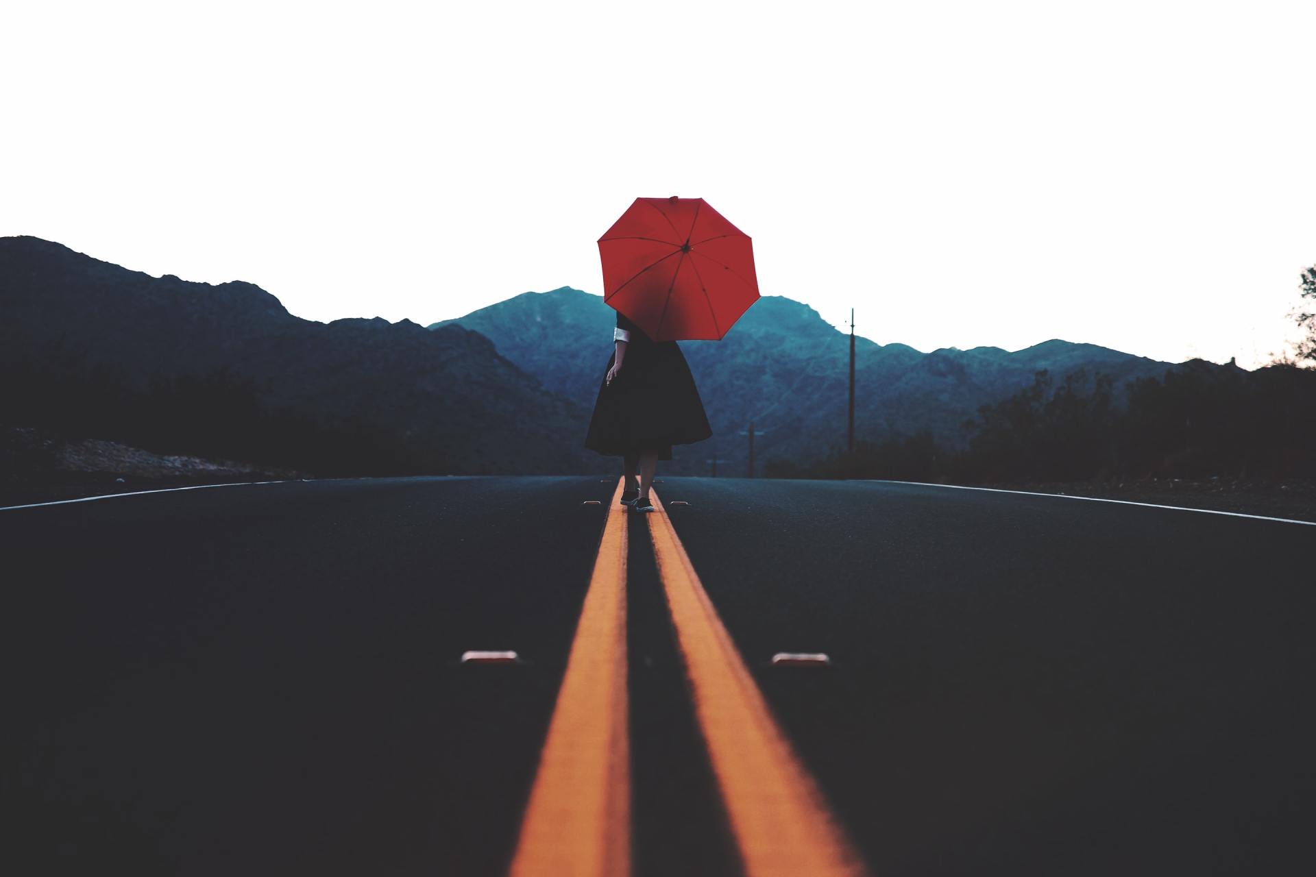 woman with umbrella in the middle of a road