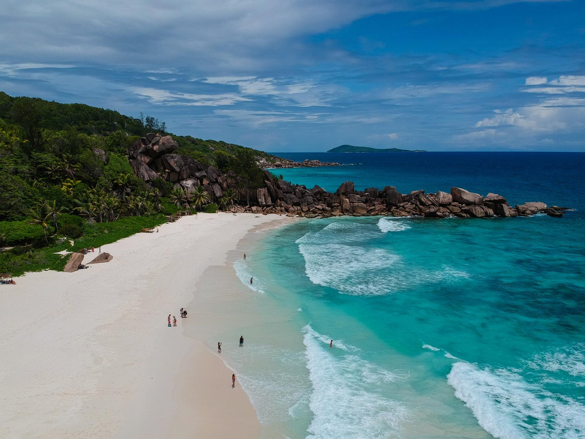 An aerial view of a beach with people walking on it and waves crashing on the shore.
