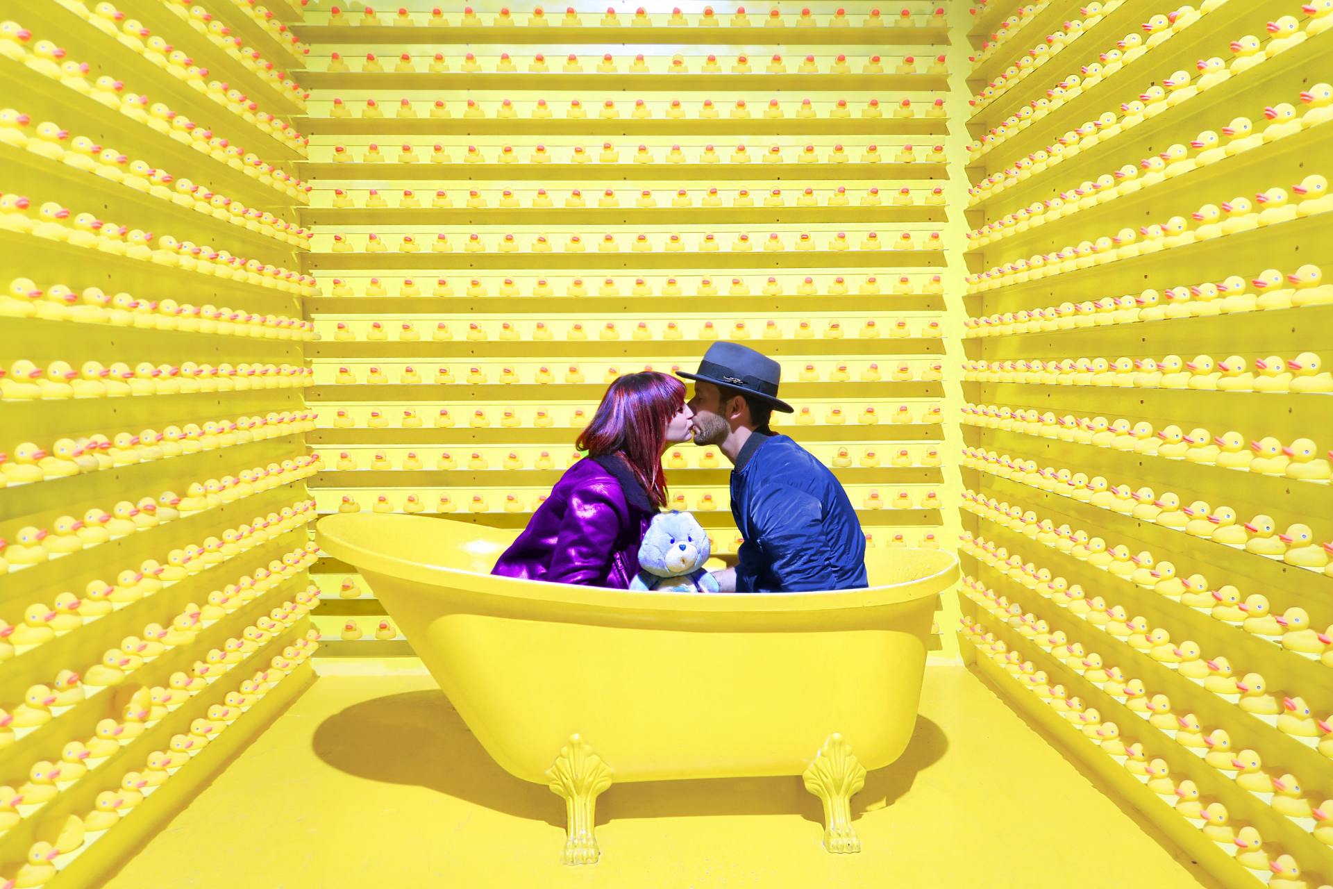 A man and a woman are kissing in a yellow bathtub.