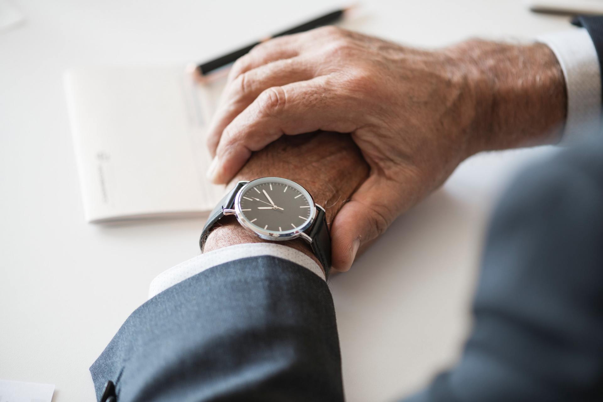 A man in a suit is looking at his watch on his wrist.