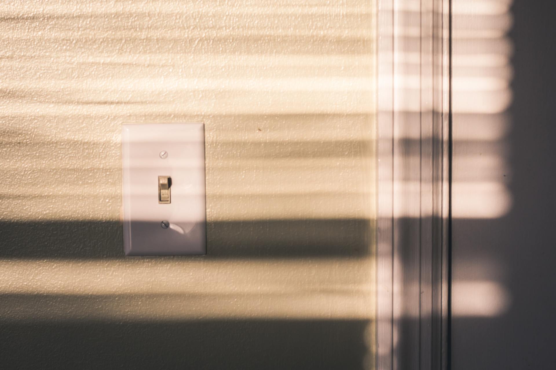 white light switch with window blind shadows