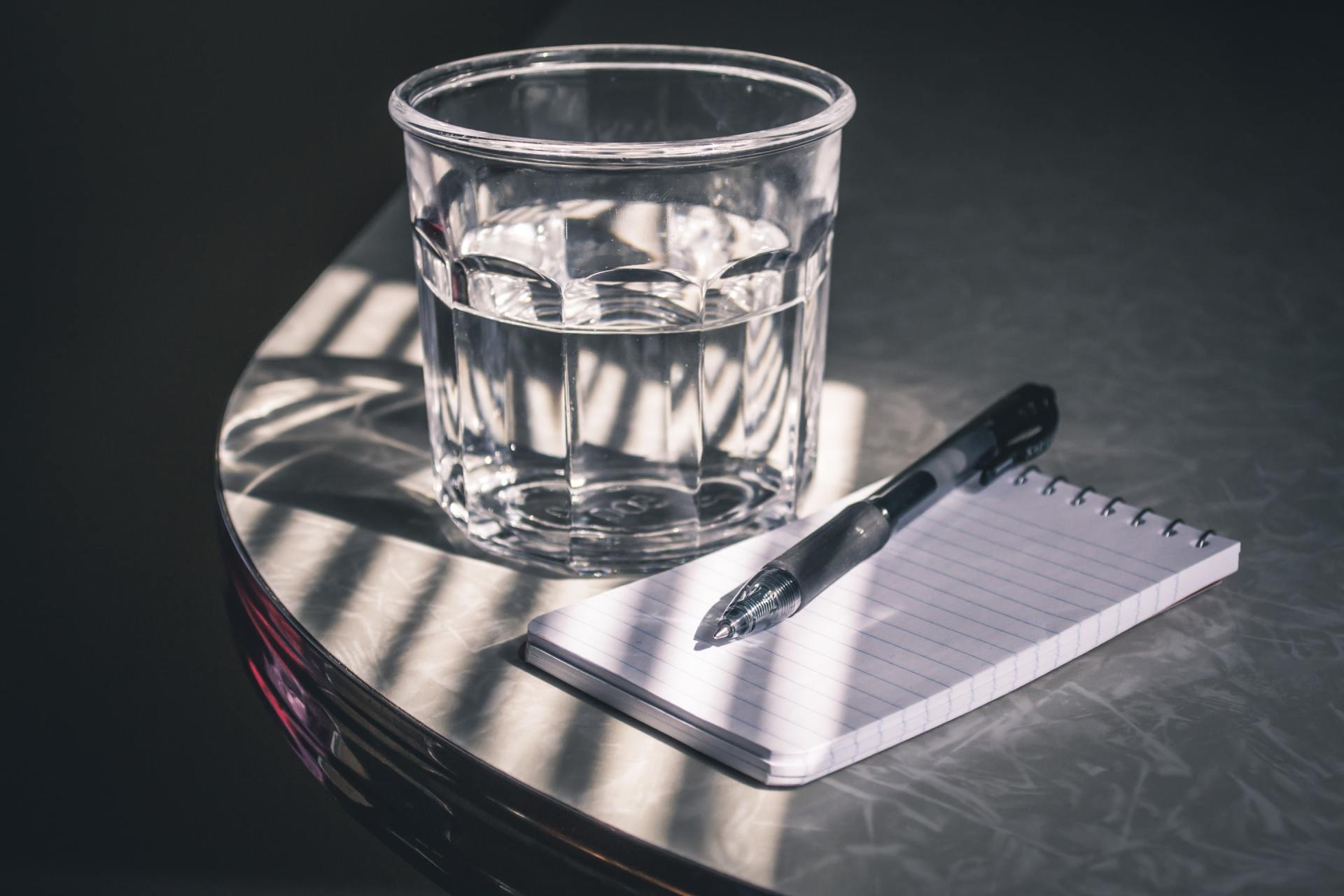 Bilde av et glass med vann, og penn og papir, mot munntørrhet ved Smil Tannlegesenter