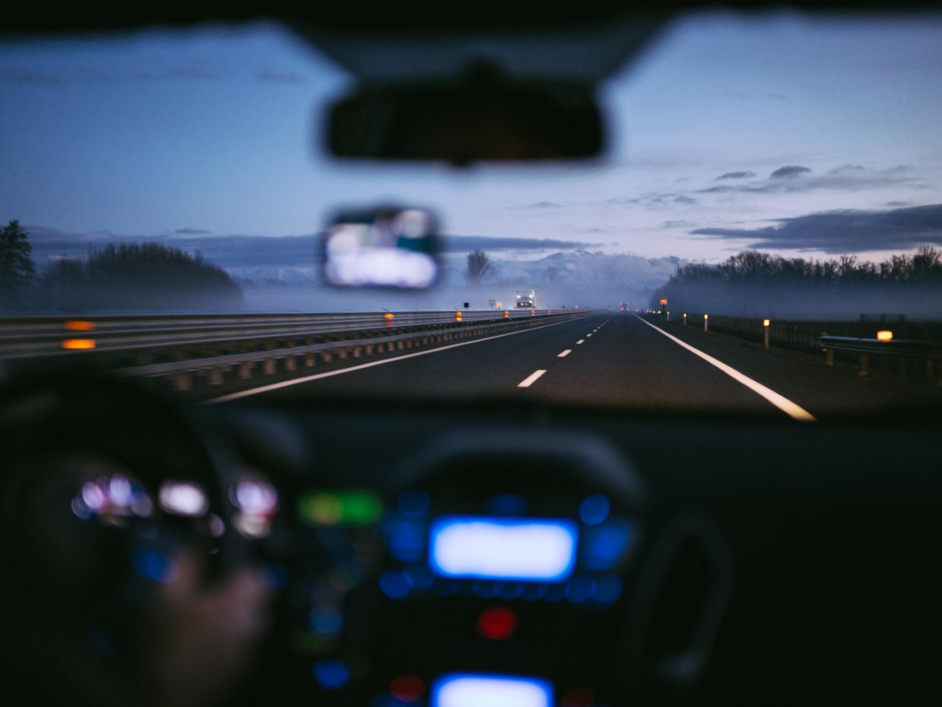 A person is driving a car on a highway at night.