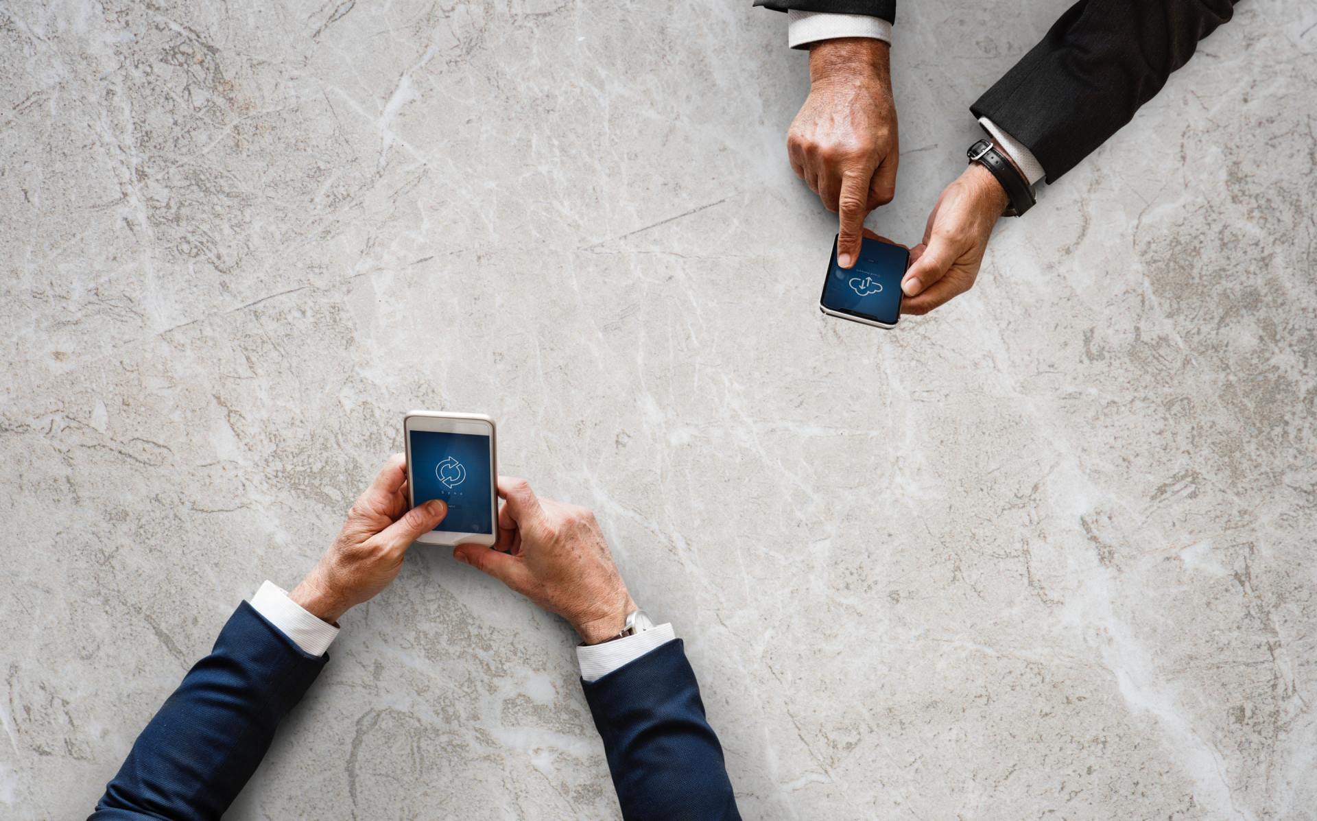 A group of people are sitting around a table looking at their phones.