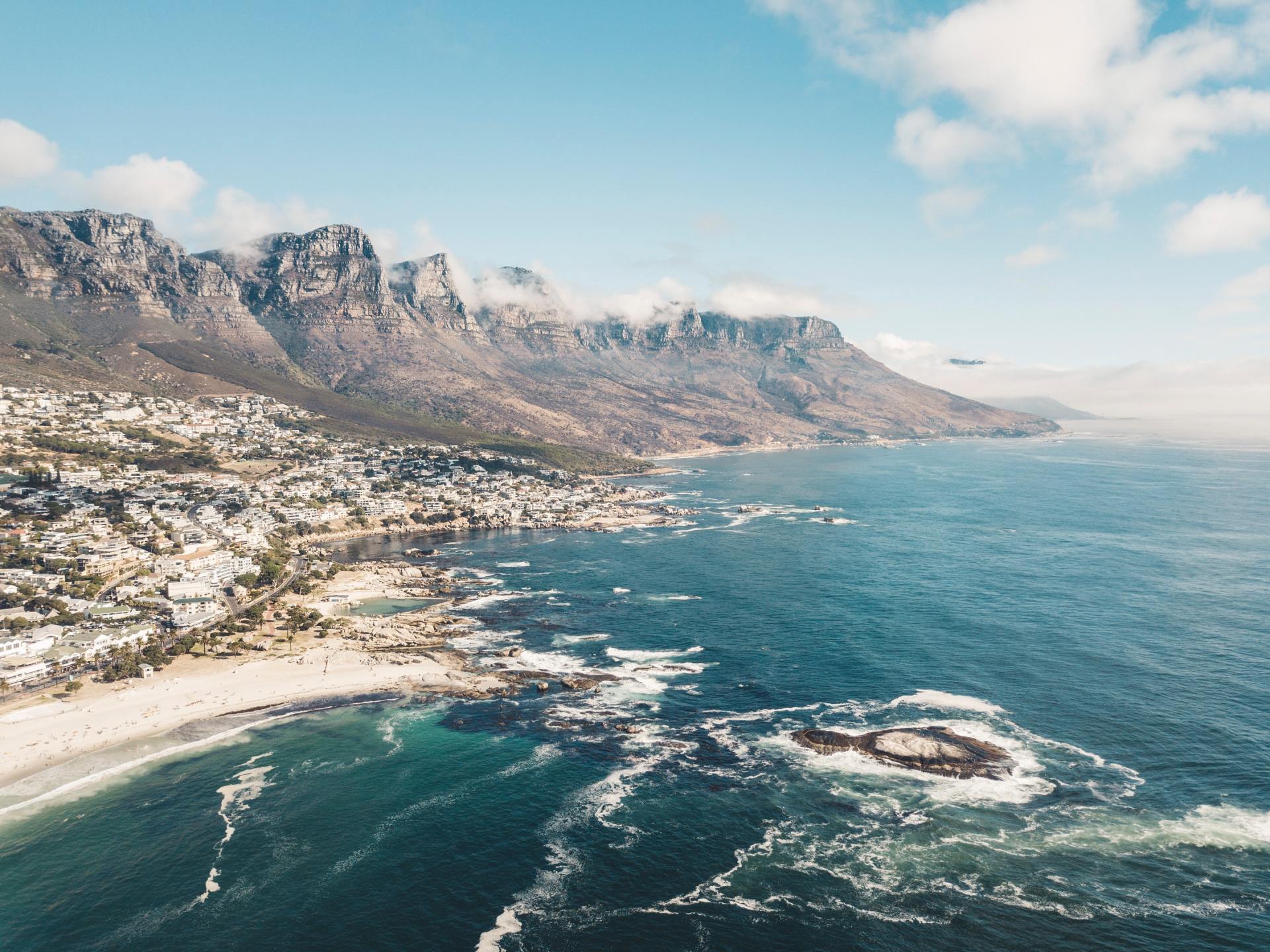An aerial view of a city next to a body of water with mountains in the background.
