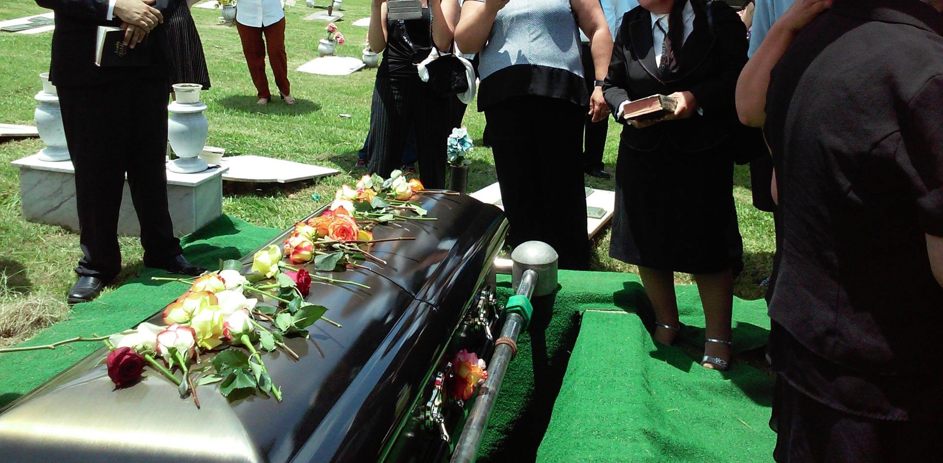 loved ones standing over casket at burial