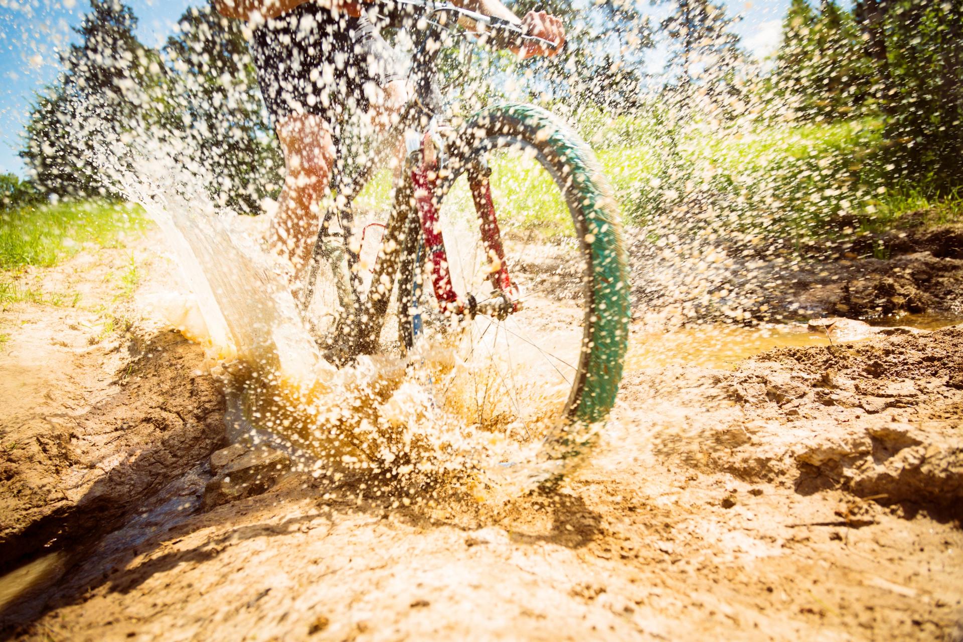 A person is riding a bike through a muddy puddle.
