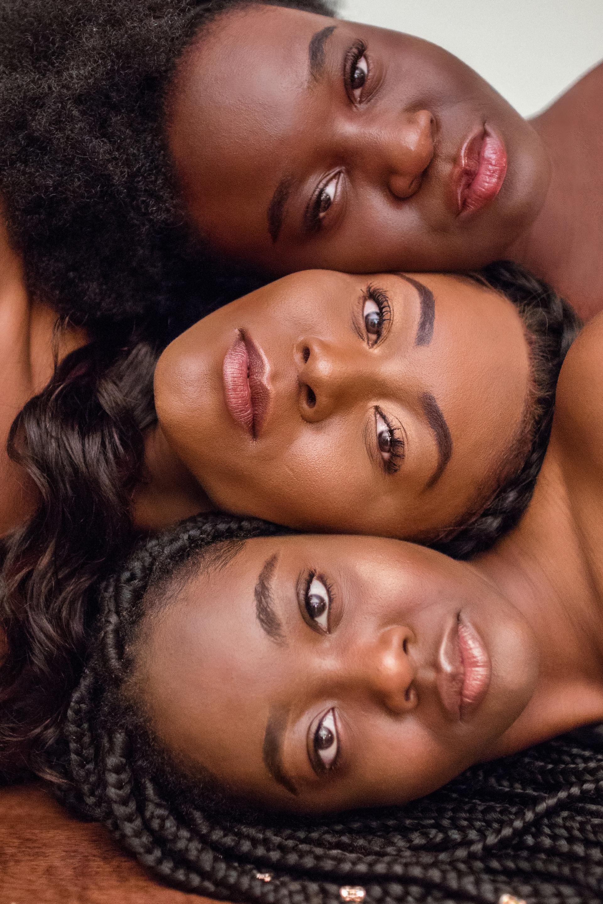 Three women are laying on top of each other and looking at the camera.