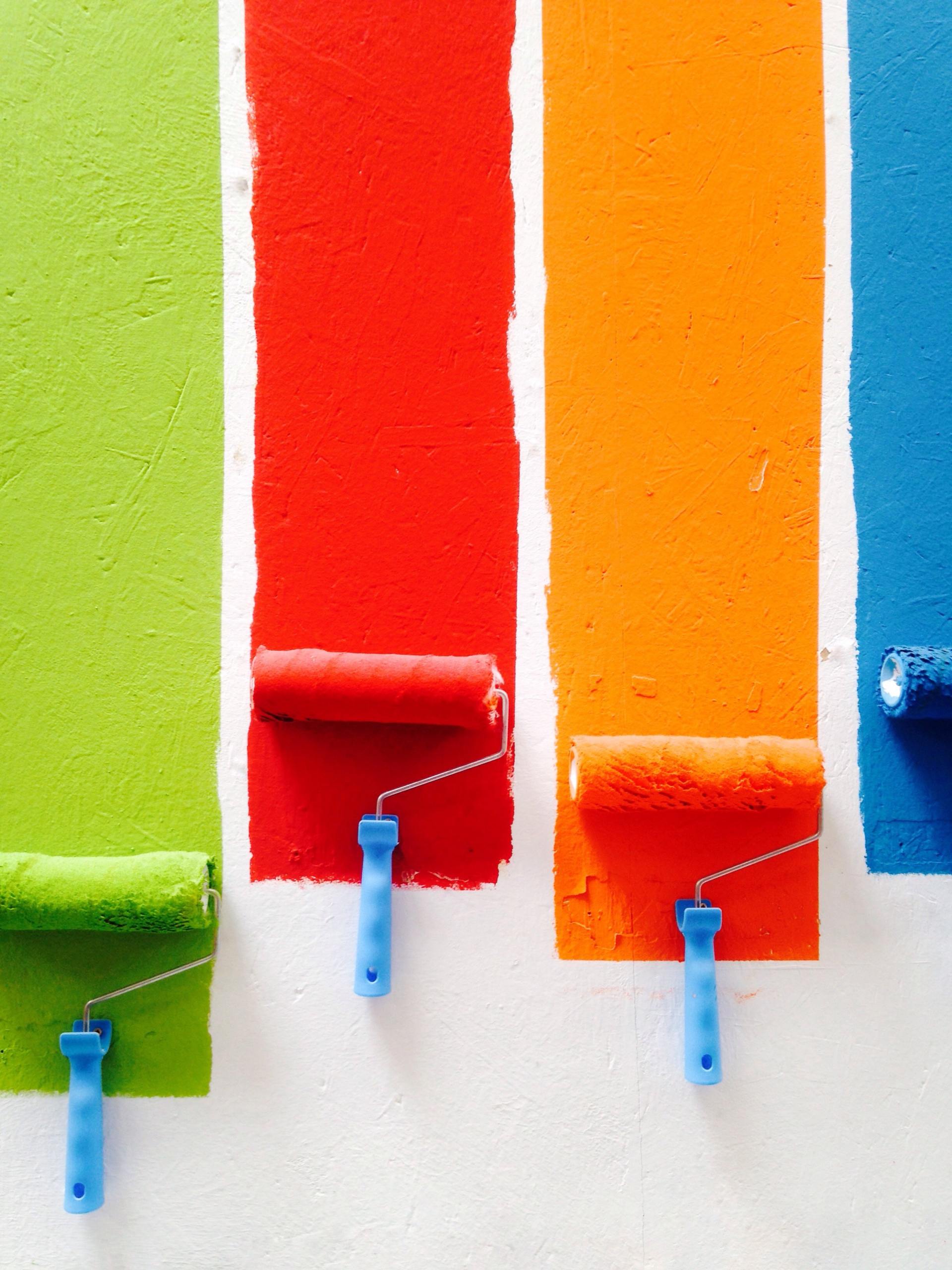 Four paint rollers with different colors of paint on them