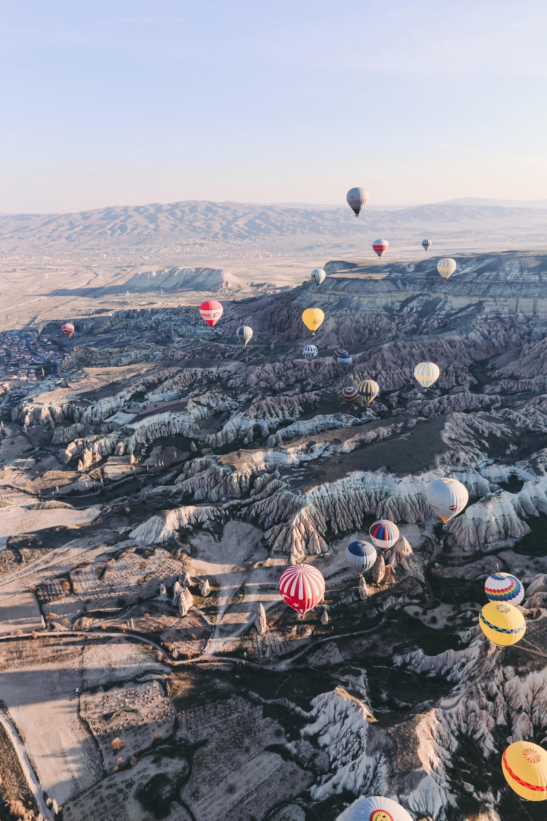 Mehrere Heißluftballons fliegen über einen Berg.