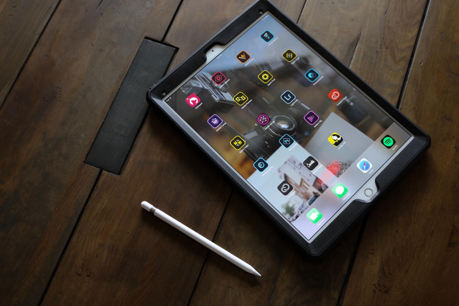 A tablet is sitting on a wooden table next to a pen