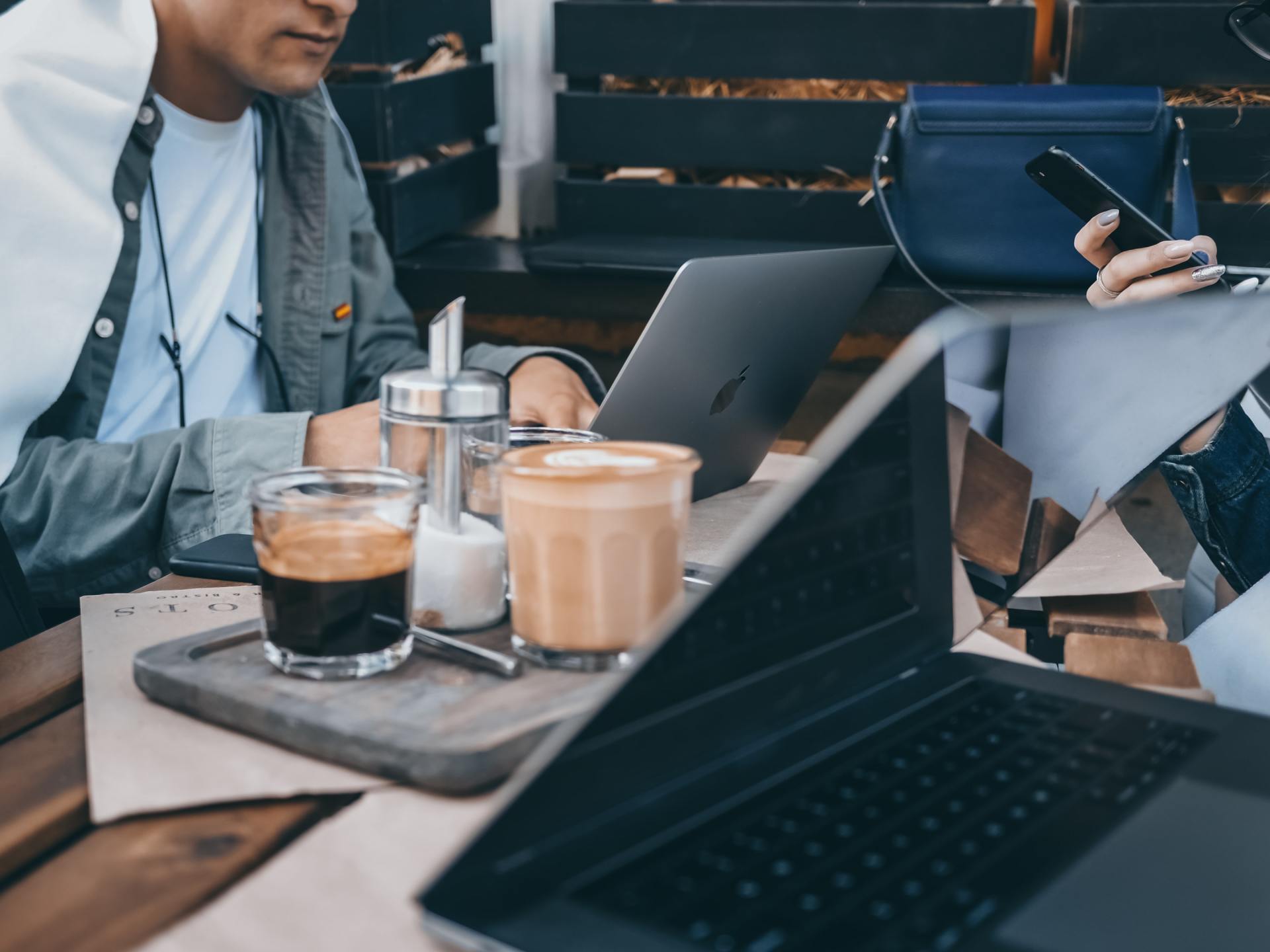 Two people are sitting at a table with laptops and drinks