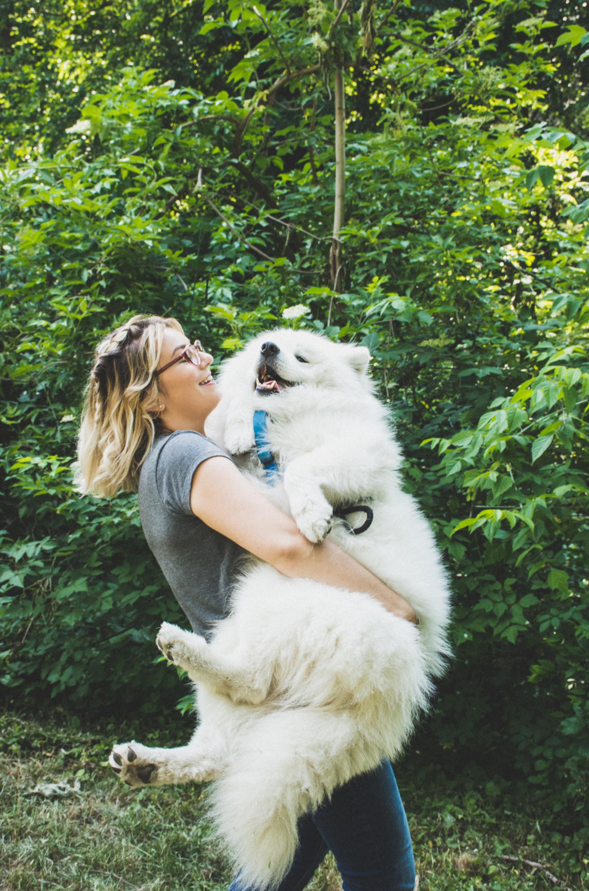 A woman is holding a large white dog in her arms.