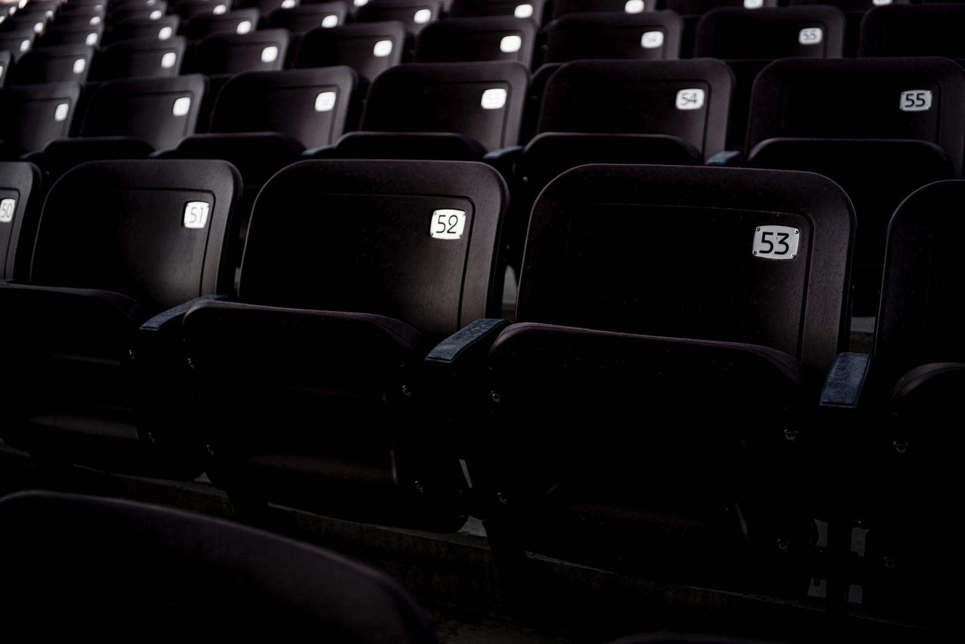 A row of empty black seats in a dark auditorium.