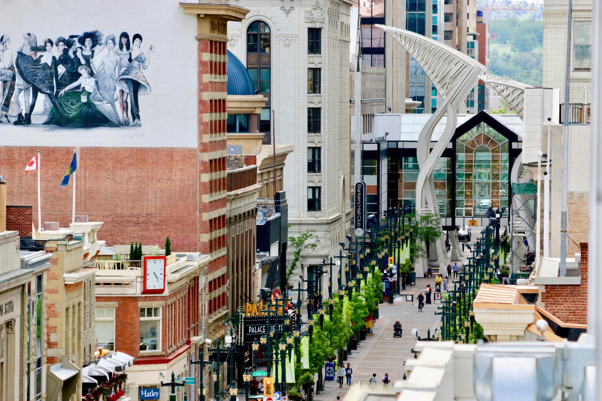 An aerial view of a city street with lots of buildings and people walking down it.