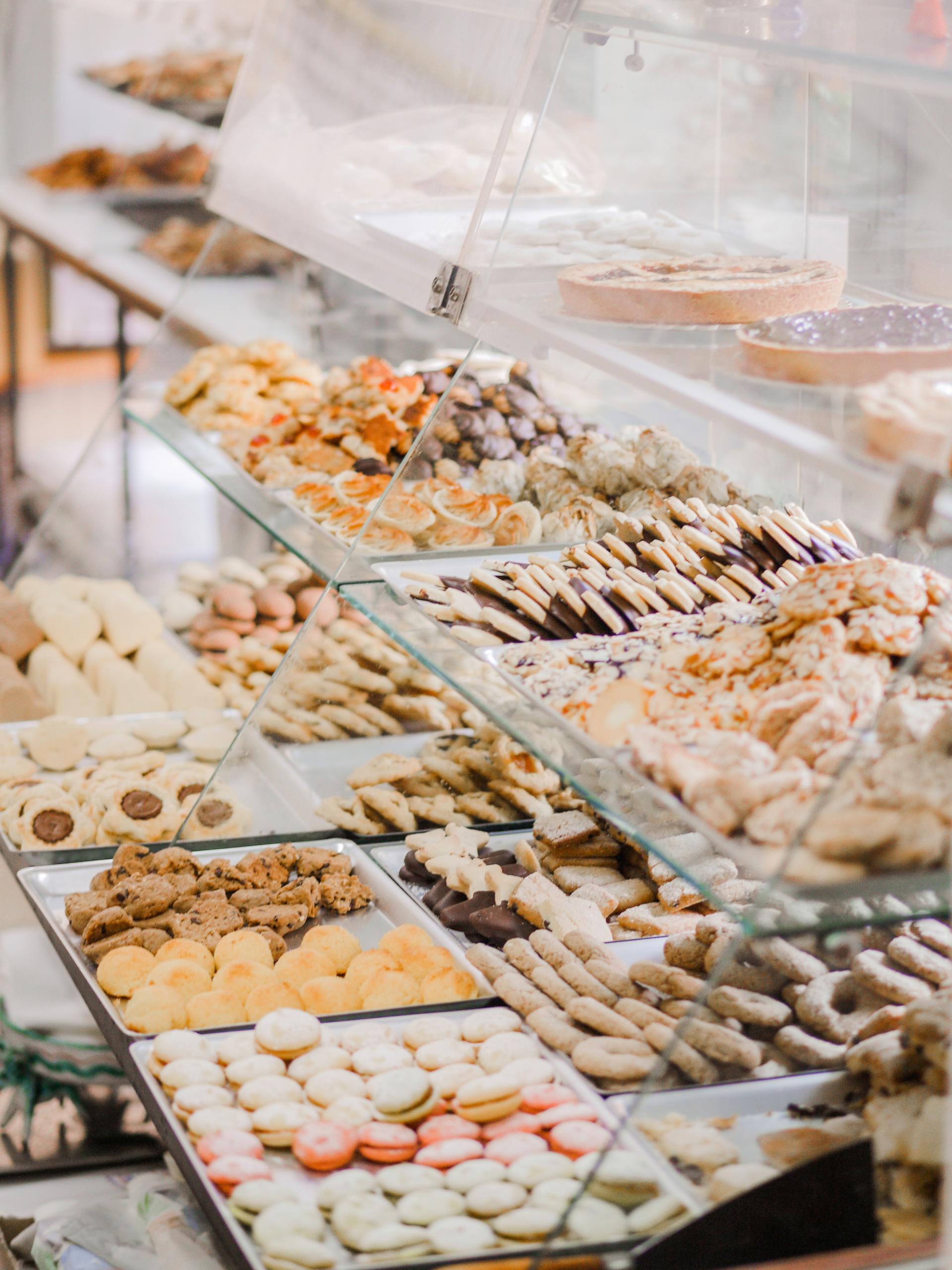 Bakery display case filled with cookies, tarts, and pastries, arranged on glass shelves.
