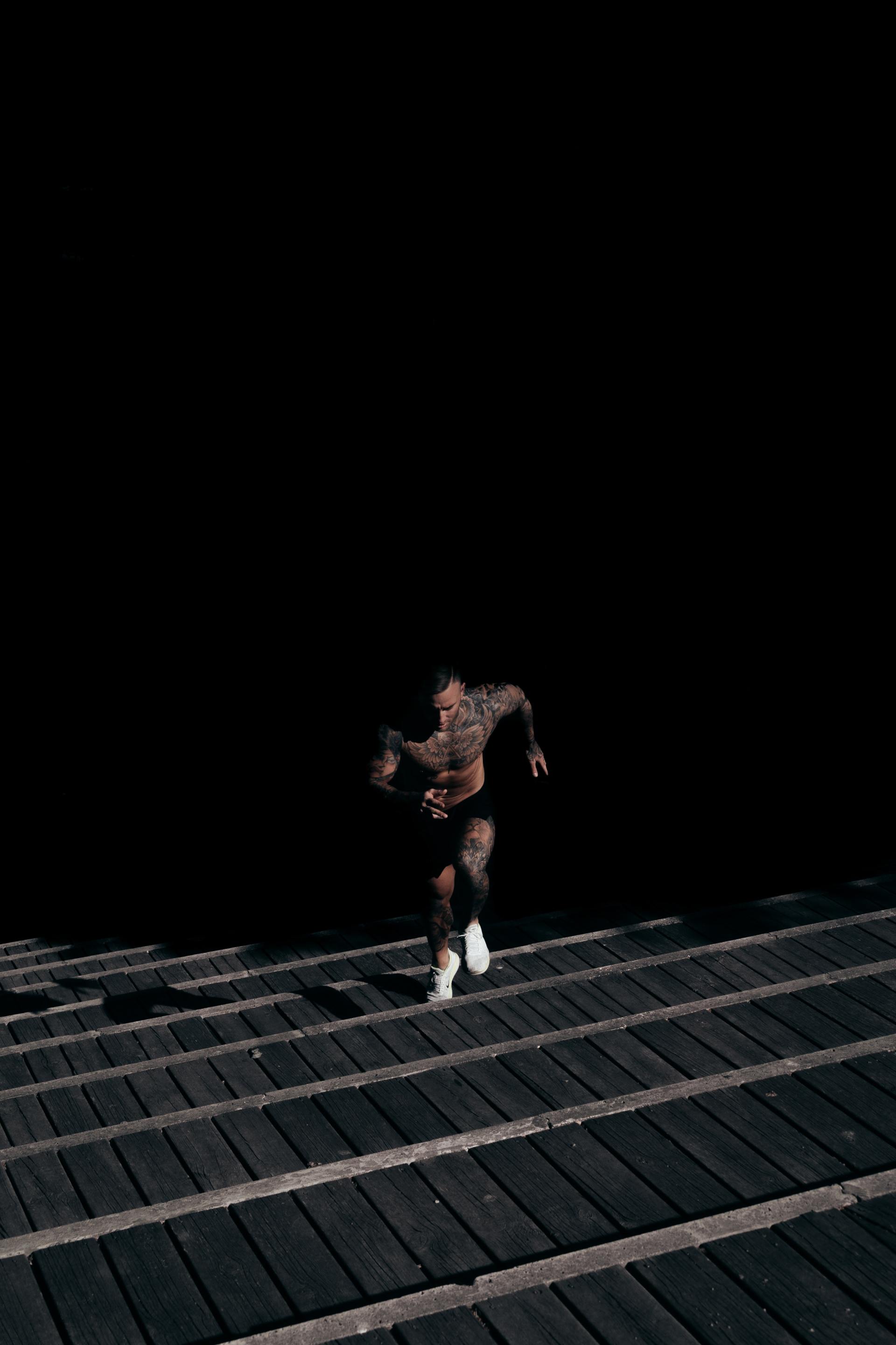 A man is running down a set of wooden stairs in the dark.