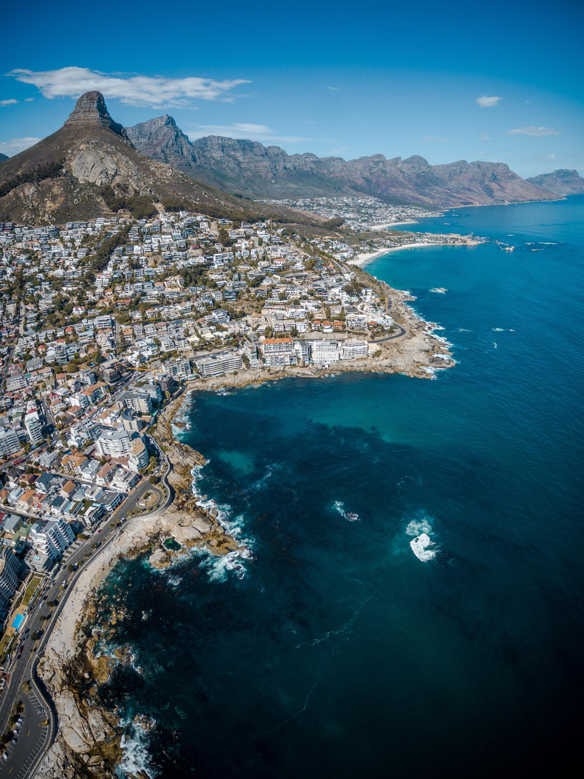 An aerial view of a city next to a body of water with mountains in the background.