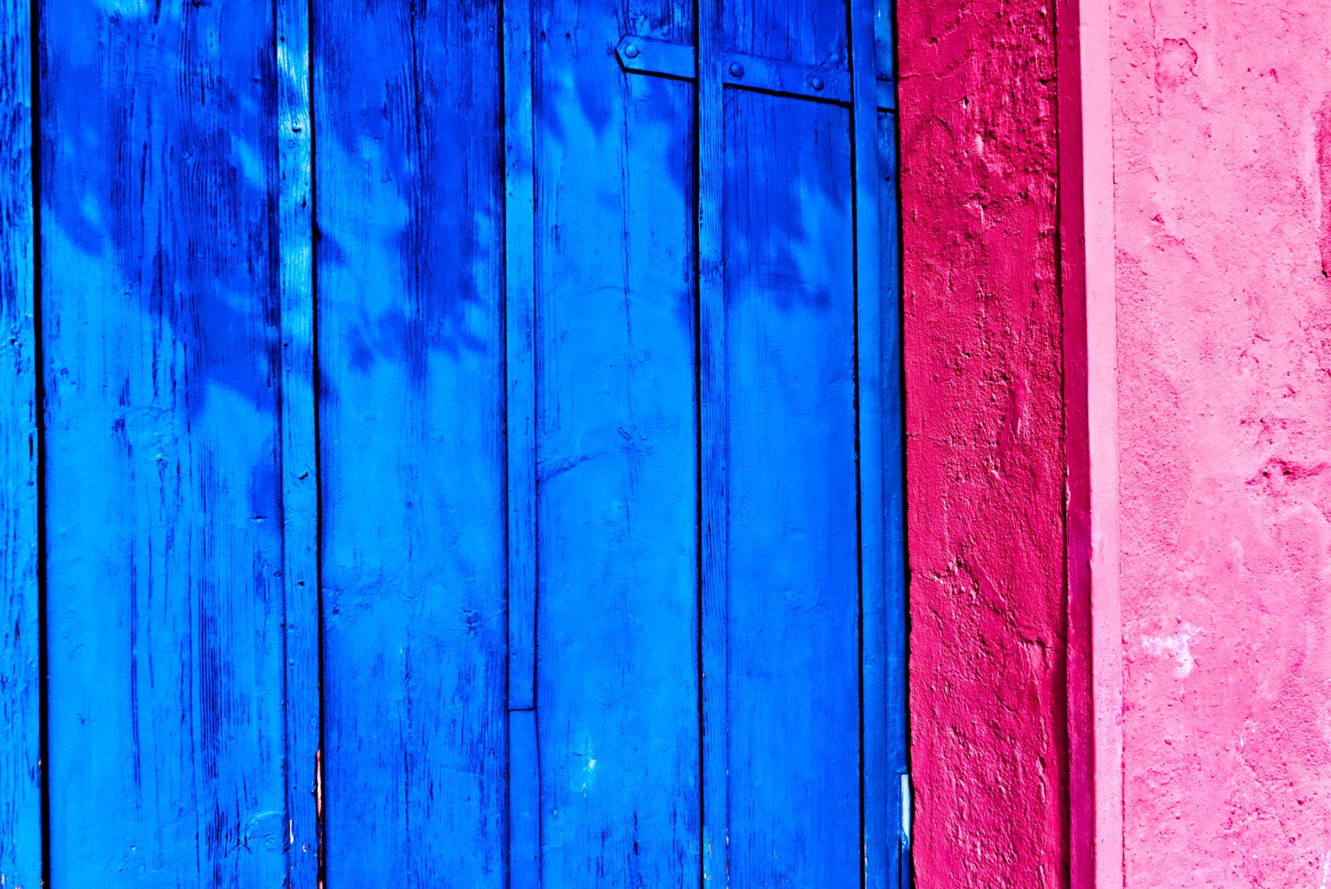 A close up of a blue and pink wooden door.