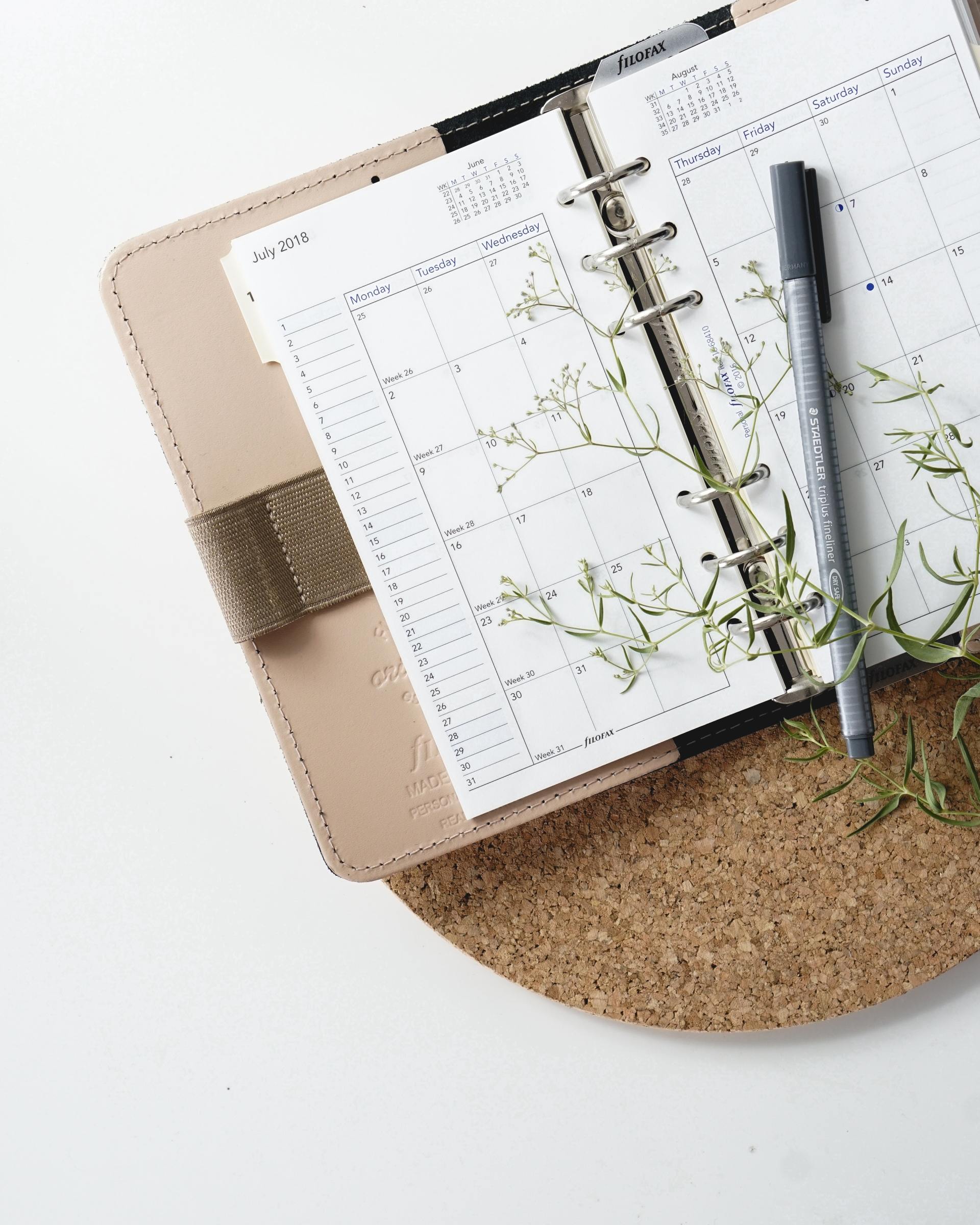 Calendar Journal lays open with a pen and greenery on top of it