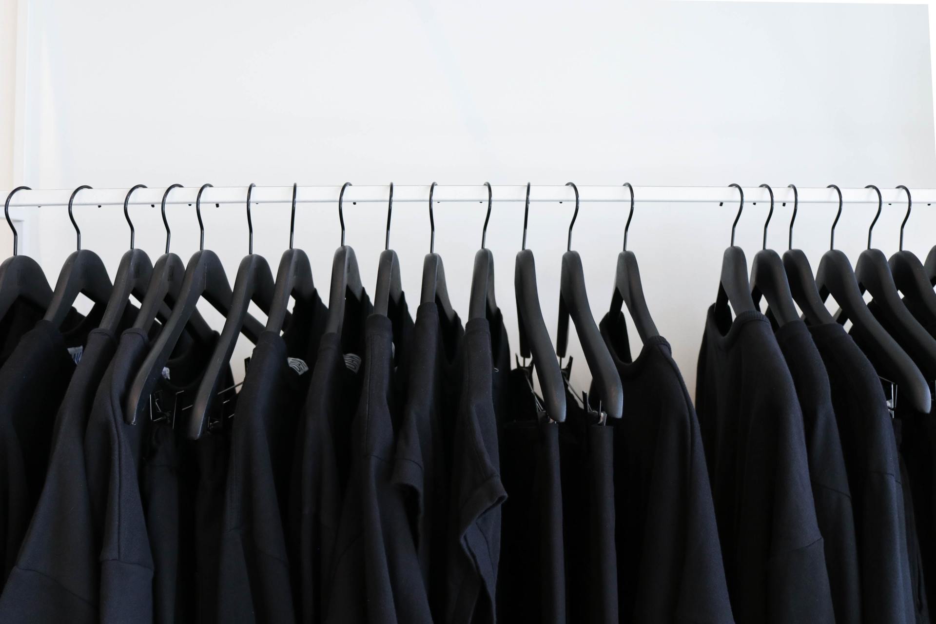 A row of black shirts hanging on a rack