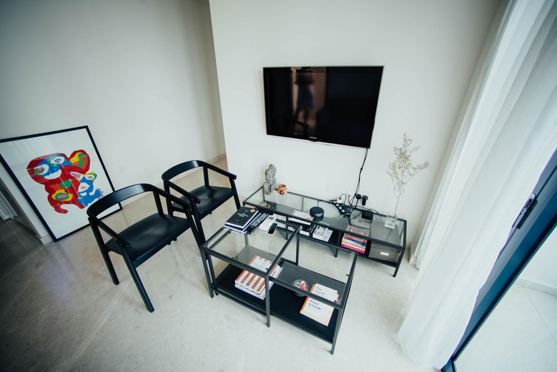 A living room with two chairs , a coffee table , and a flat screen tv.