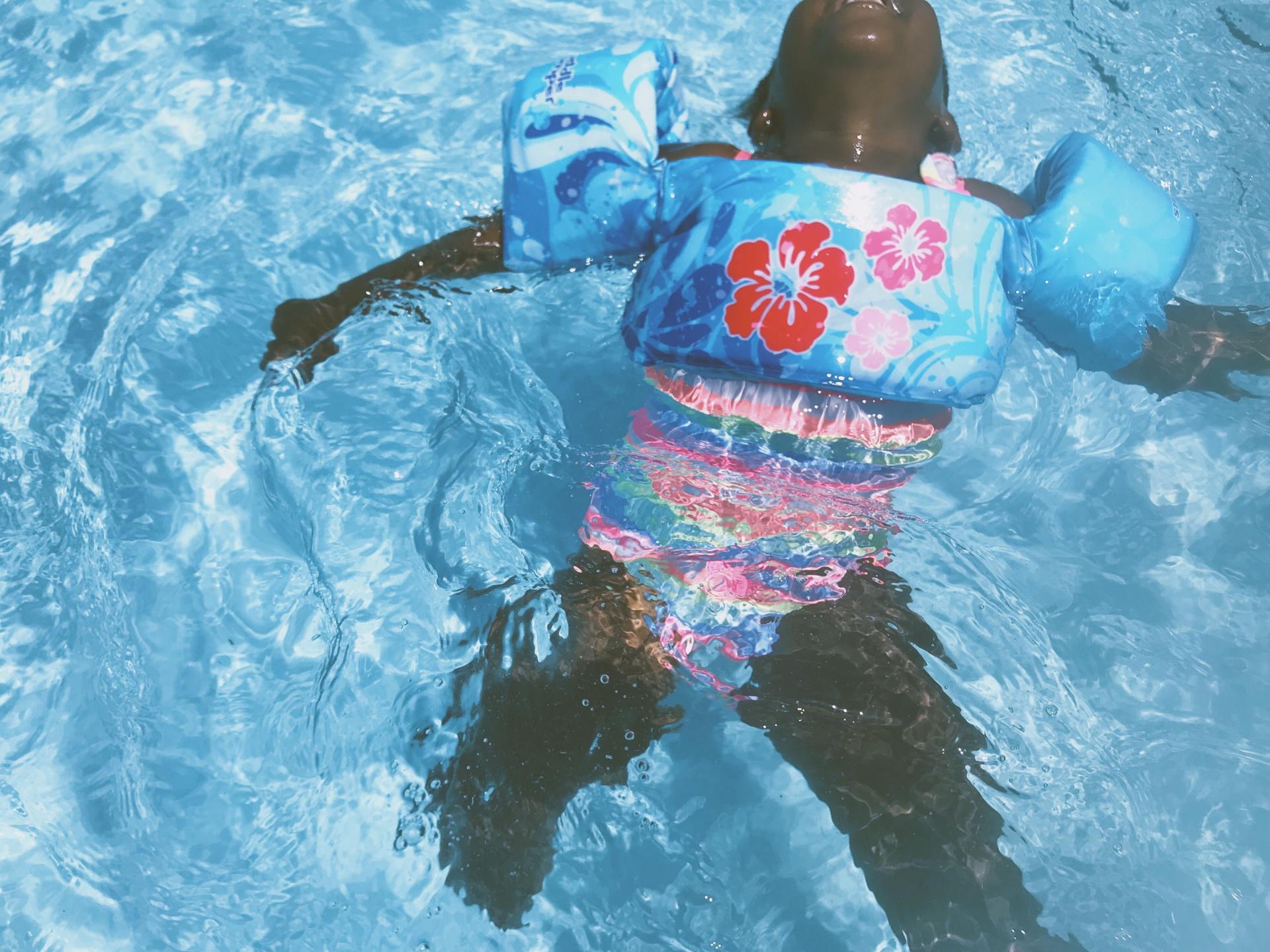 A child wearing a life jacket is swimming in a pool