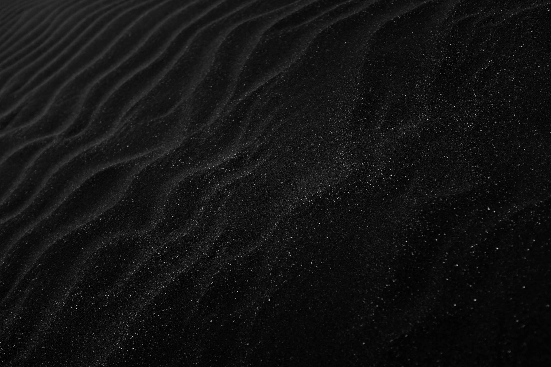 a black and white photo of a sand dune with stars in the background .