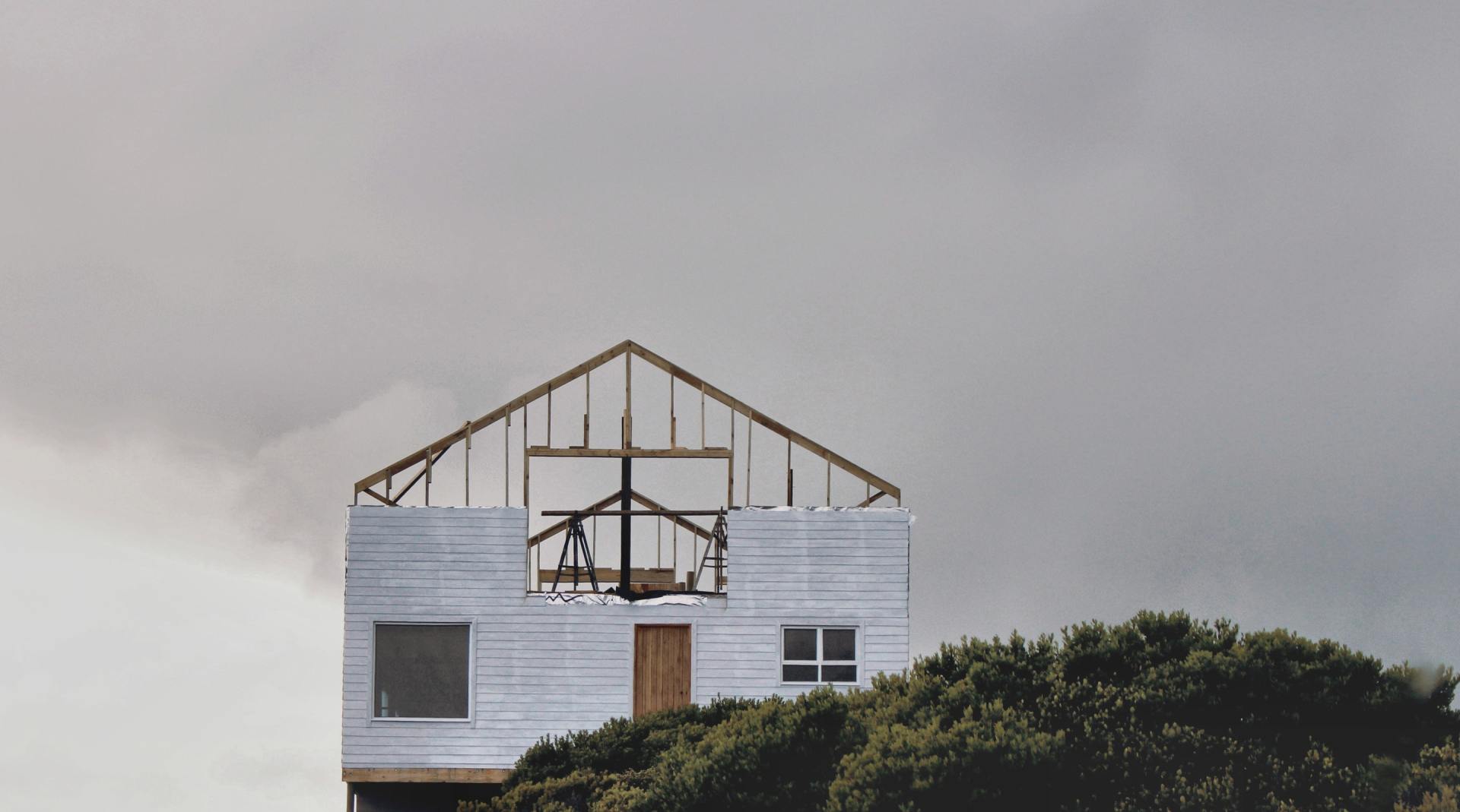 A large white house is being built on top of a hill.