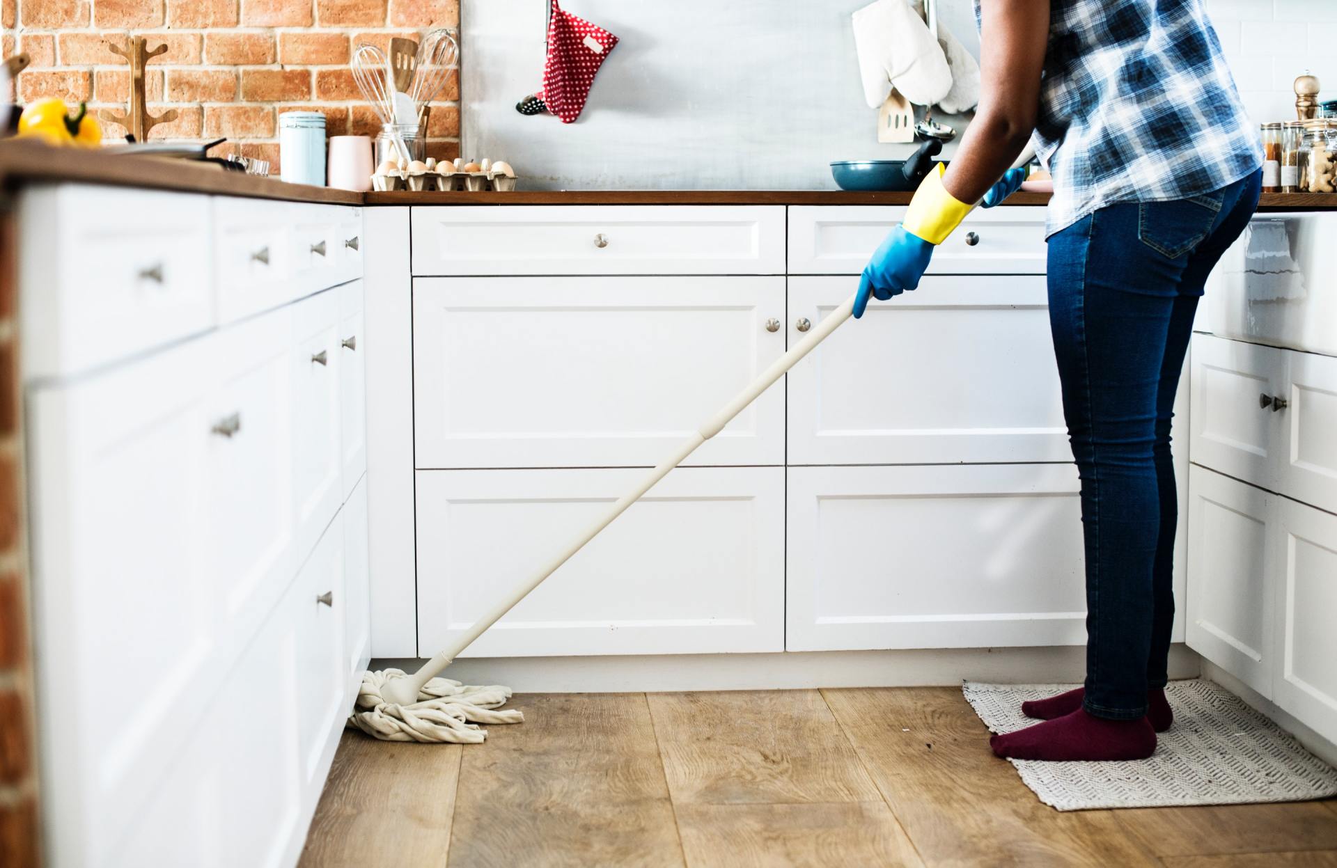 person standing in the kitchen mopping the floor