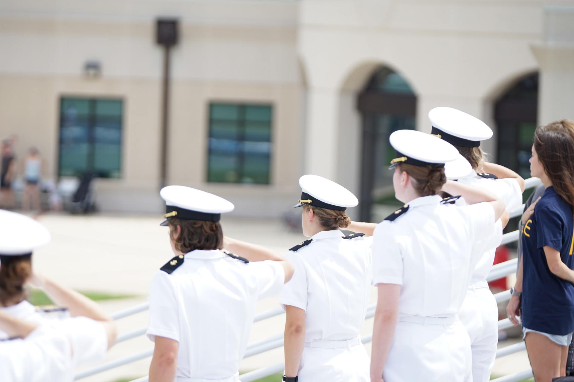 A group of women in military uniforms salute in front of a building
