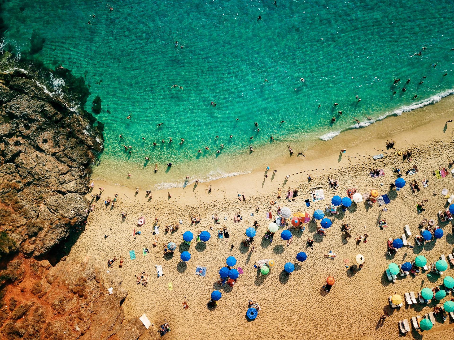 An aerial view of a beach filled with people and umbrellas.