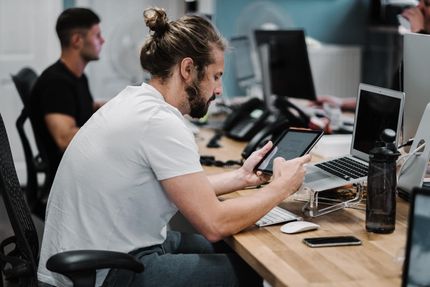 A man is sitting at a desk using a tablet computer.