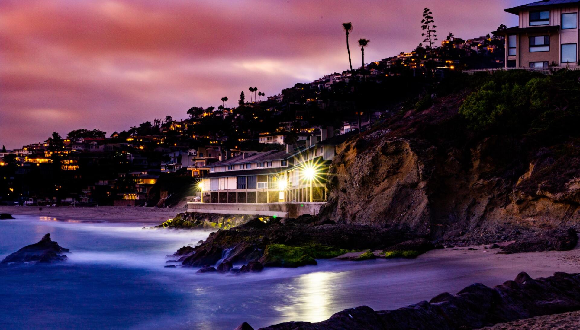 A house on a cliff overlooking the ocean at night